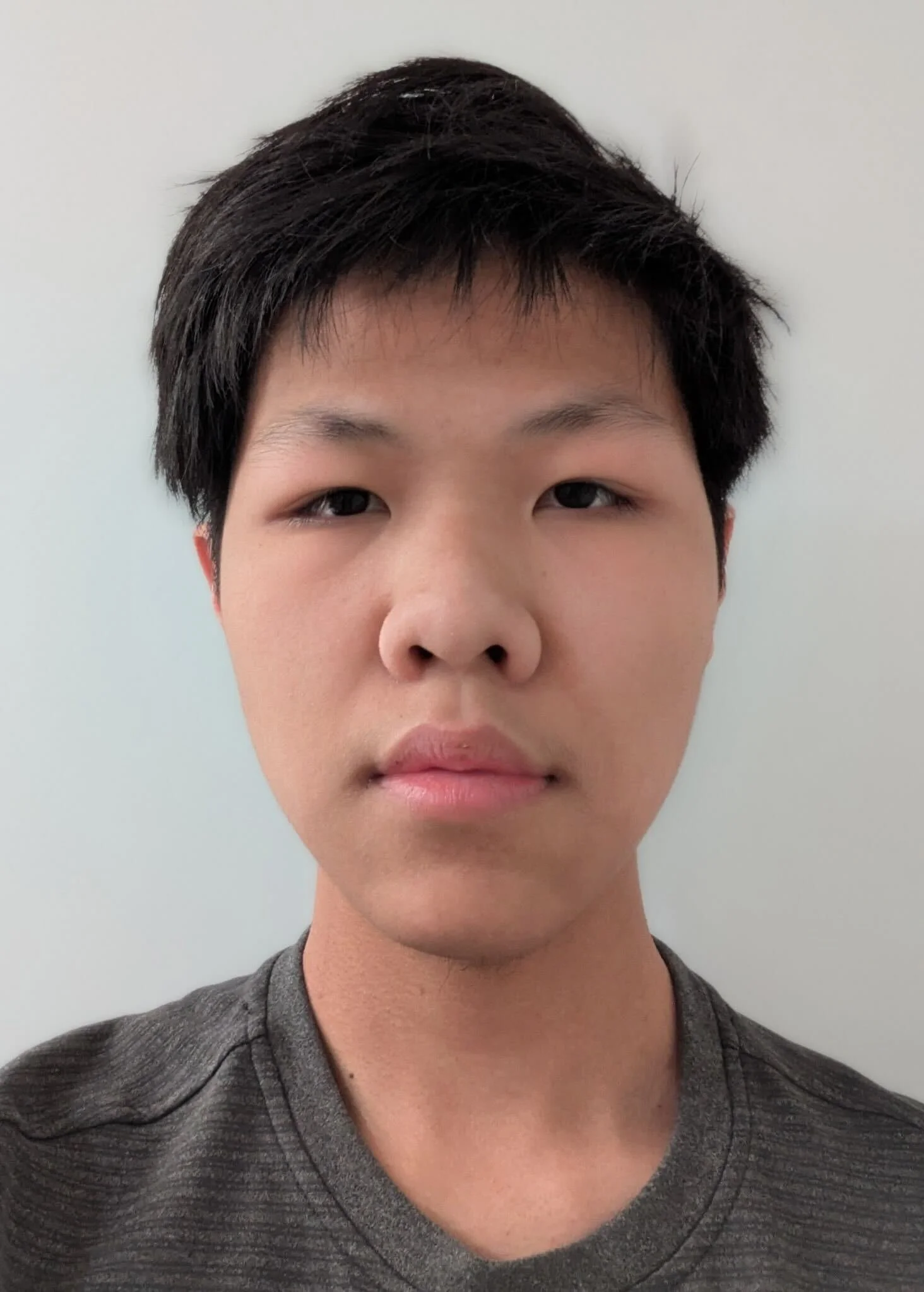 A young man with straight hair looking directly at the camera