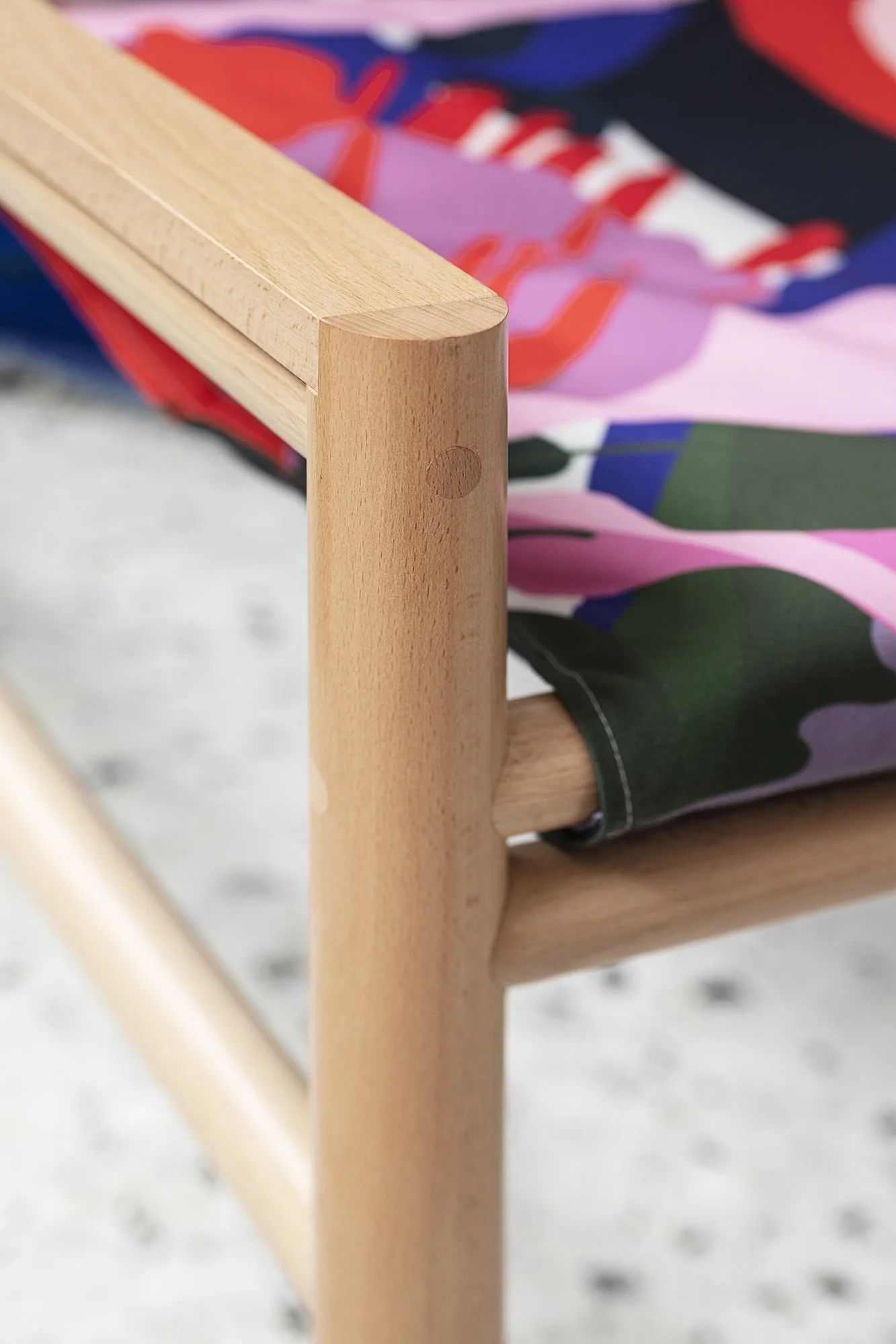 Détail d'une chaise en bois avec un tissu coloré.
