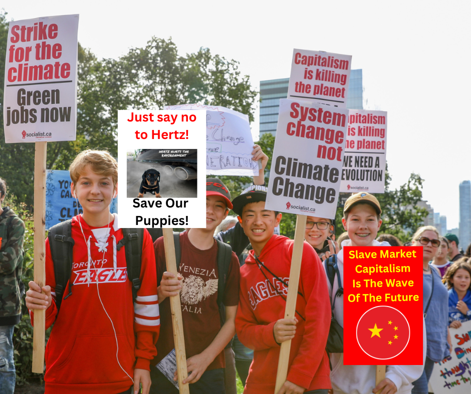 Group of children at a climate protest holding signs advocating action against capitalism and climate change, with one sign saying "Just say no to Hertz! Save Our Puppies!" and another saying "Slave Market Capitalism Is The Wave Of The Future" with a Chinese flag.