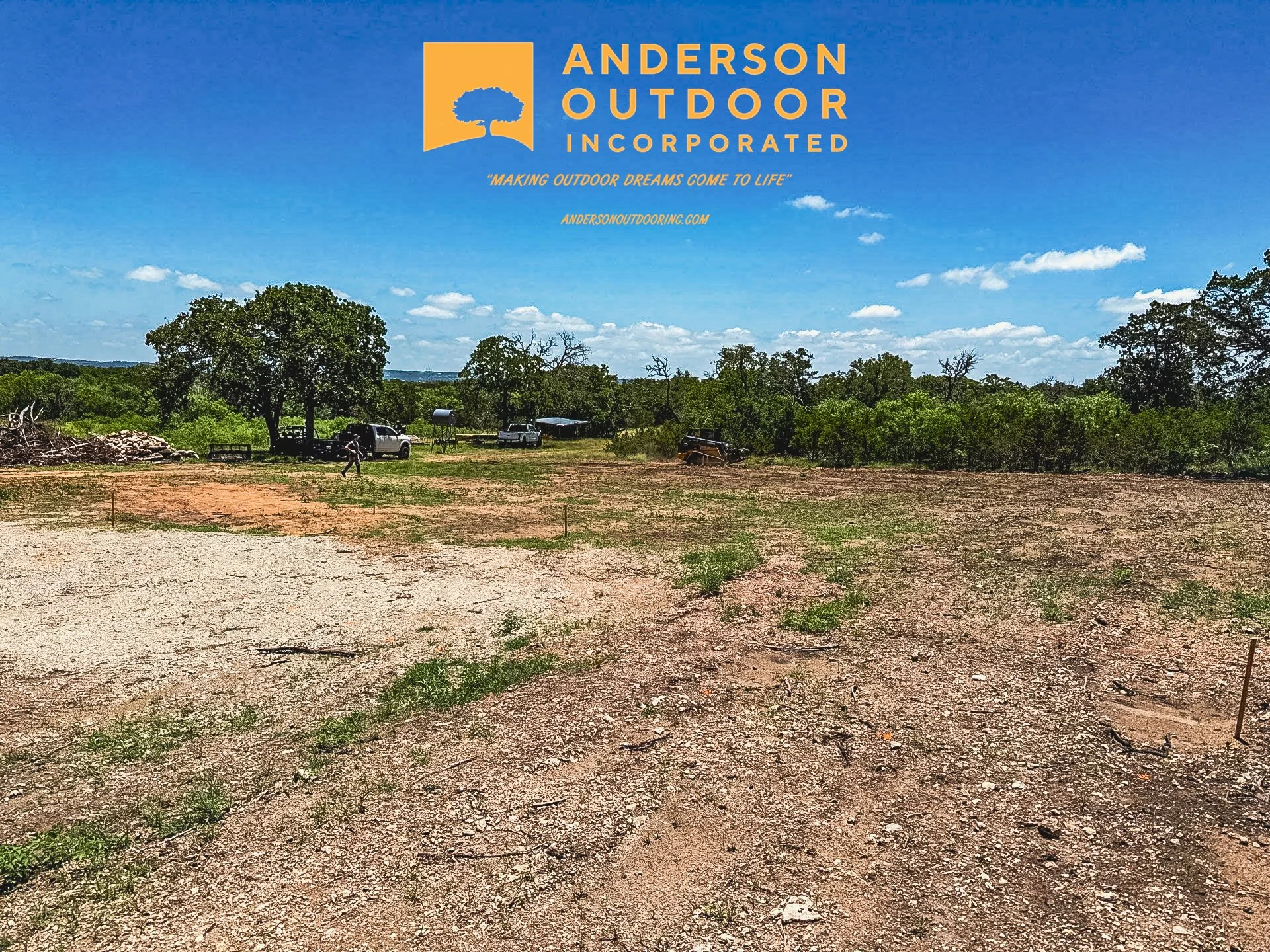A dirt lot with sparse grass, trees, and a few vehicles in the background under a partly cloudy sky. The upper left corner has a logo for Anderson Outdoor Incorporated with a tree icon and text.