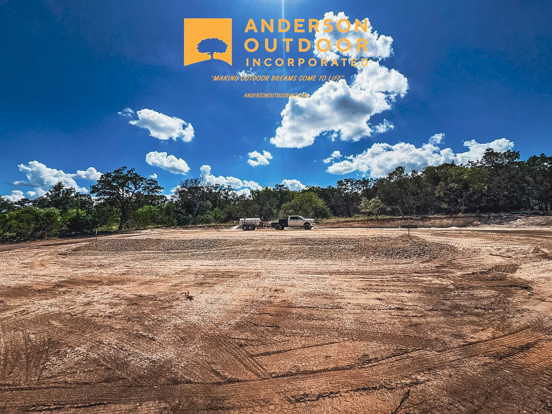 Construction site with a dirt ground, a white pickup truck, and trees in the background under a blue sky with white clouds, featuring the Anderson Outdoor Incorporated logo and slogan at the top.