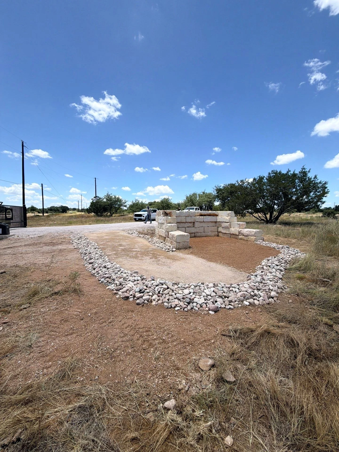 Finished rock-lined swale around a gravel pad with limestone blocks in the Texas Hill Country.