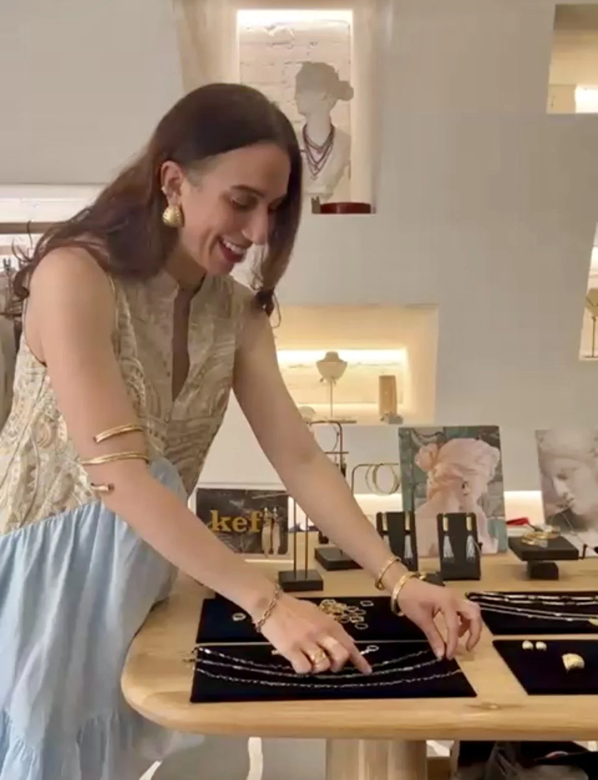 Kefi designer Stephanie Alman arranging sculptural jewelry on displays in New York City