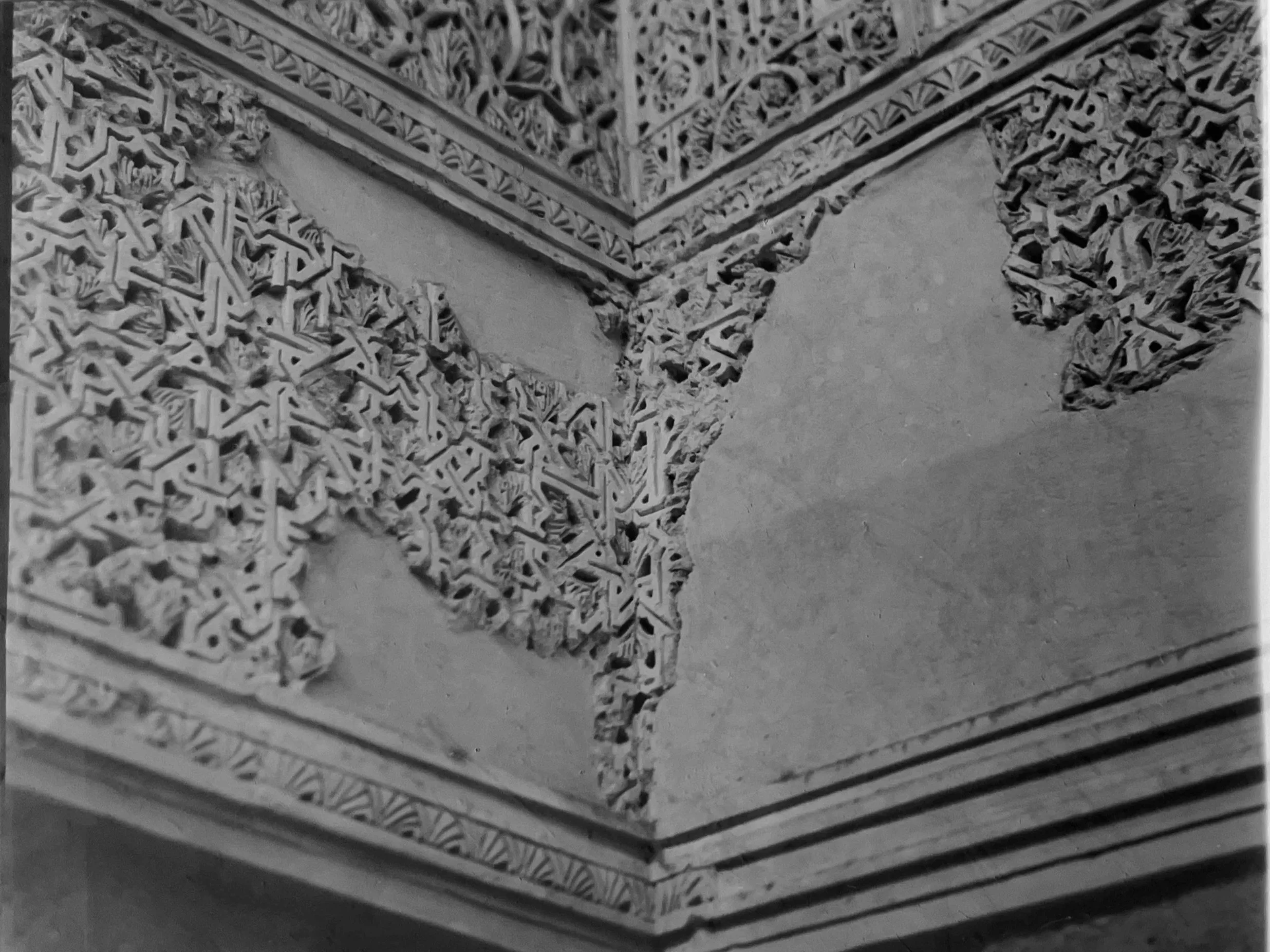 Close-up of intricate carved architectural details on a wall corner, with ornate patterns and decorative trims in black and white.