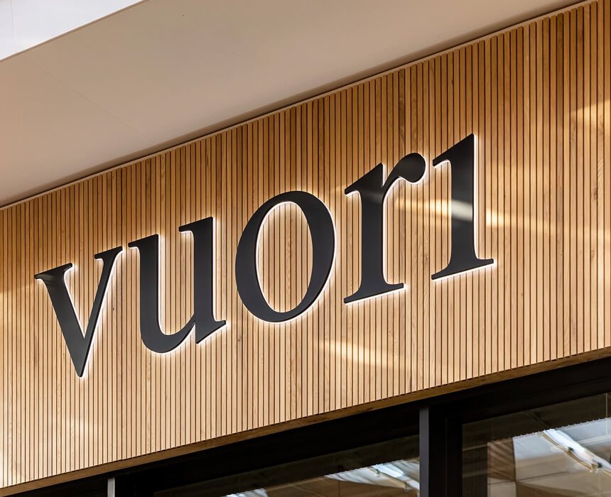 Close-up of a storefront sign with the word 'vuori' in black letters on a wooden slat background.
