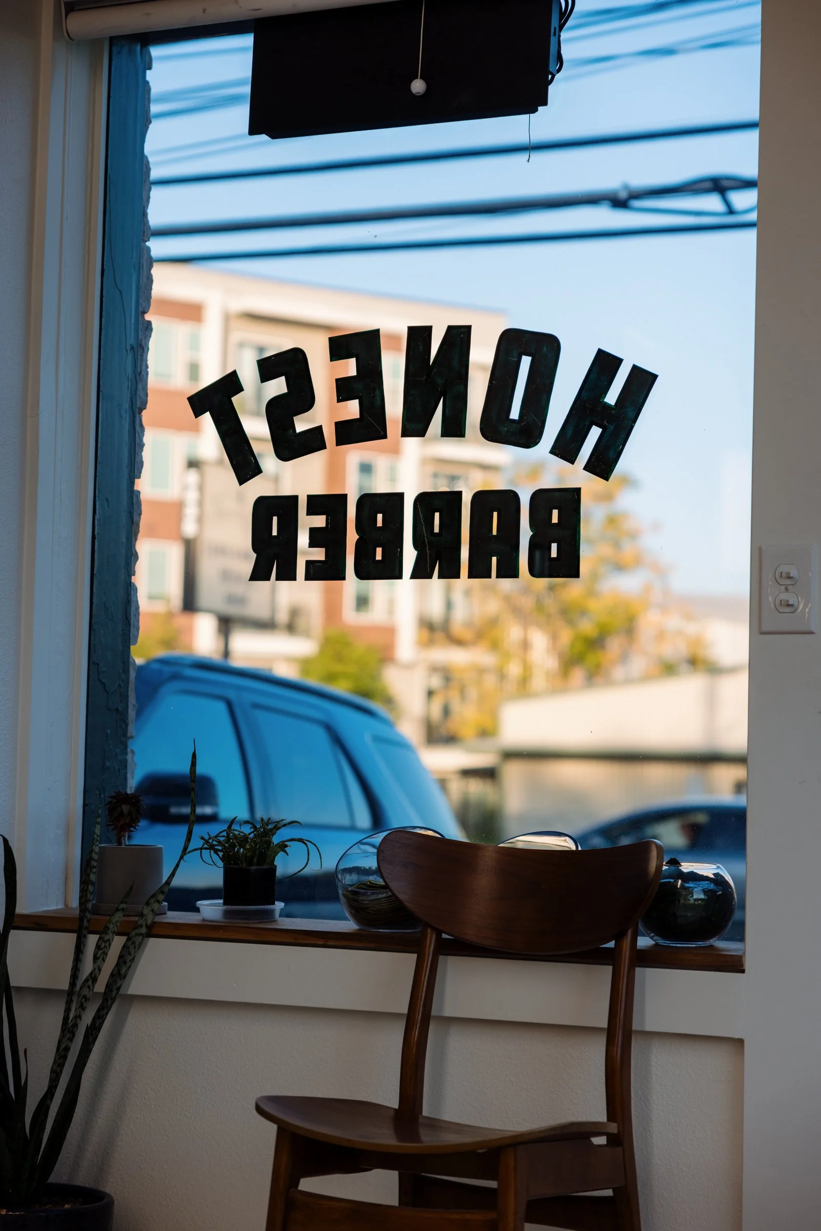Front window view of Honest Barber barbershop in Austin Texas with street scene outside.