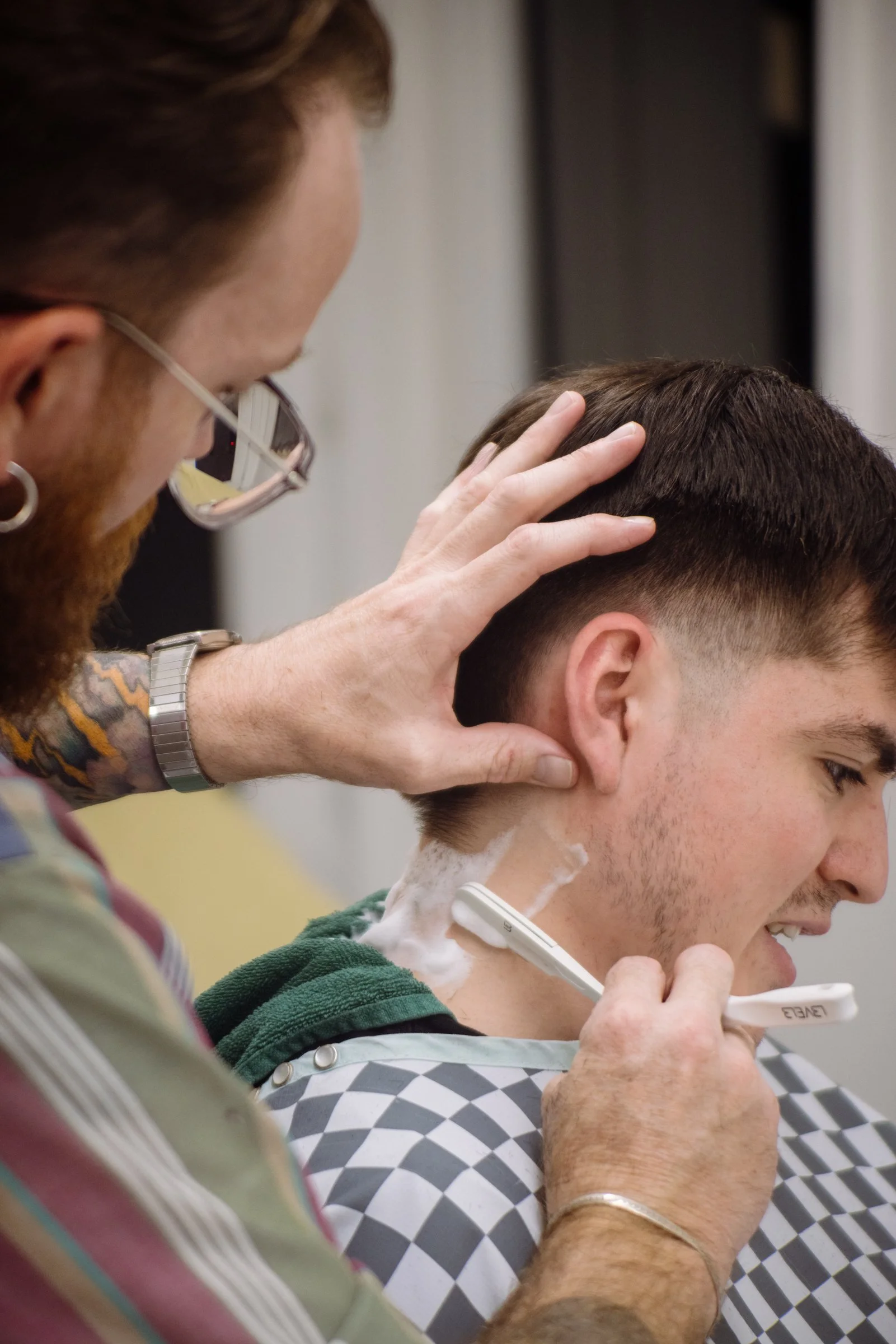 Barber performing a straight razor neck shave at Honest Barber in Austin, showcasing traditional barbering services.