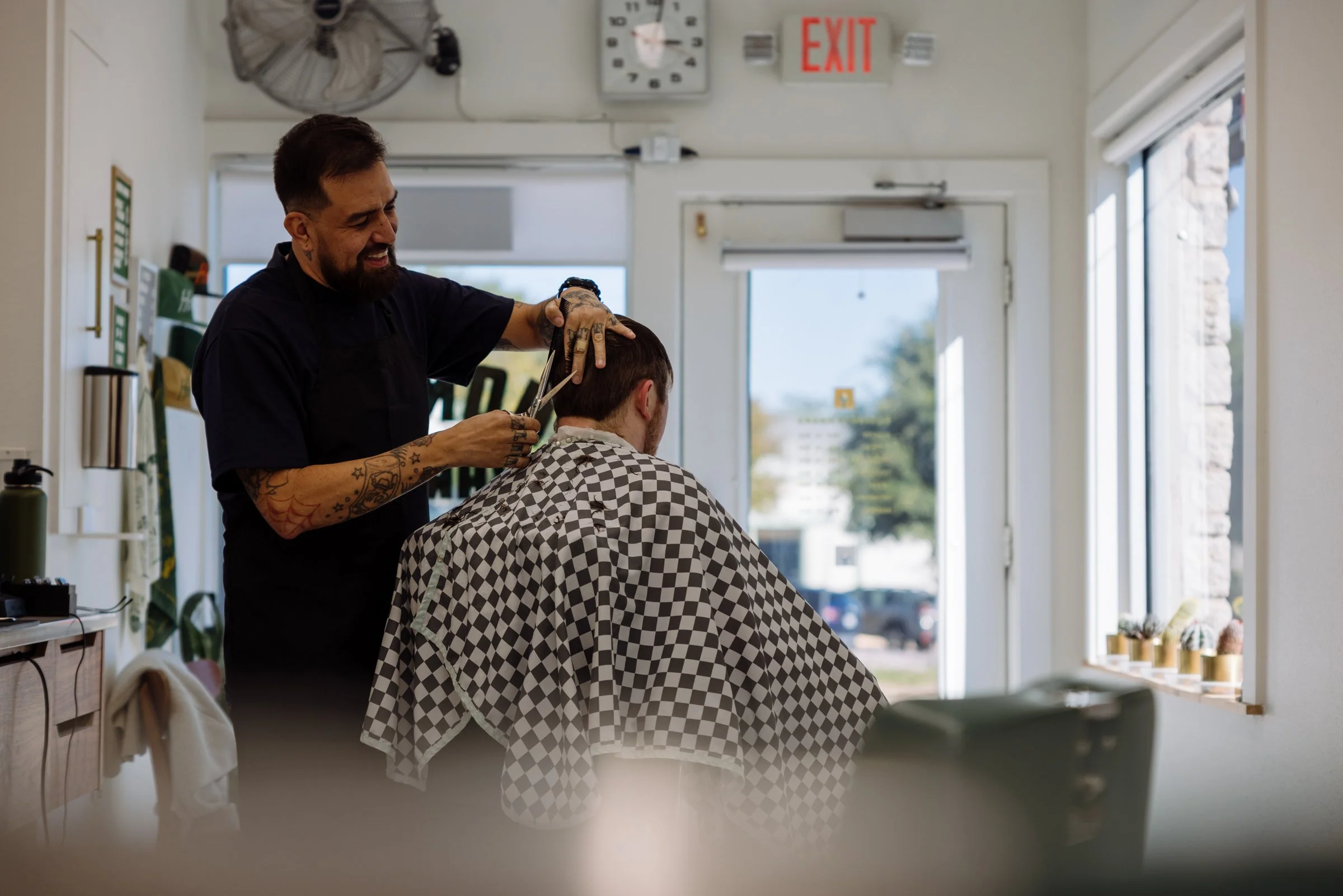 Austin barber giving a precision men’s haircut inside Honest Barber barbershop with natural light and classic interior.