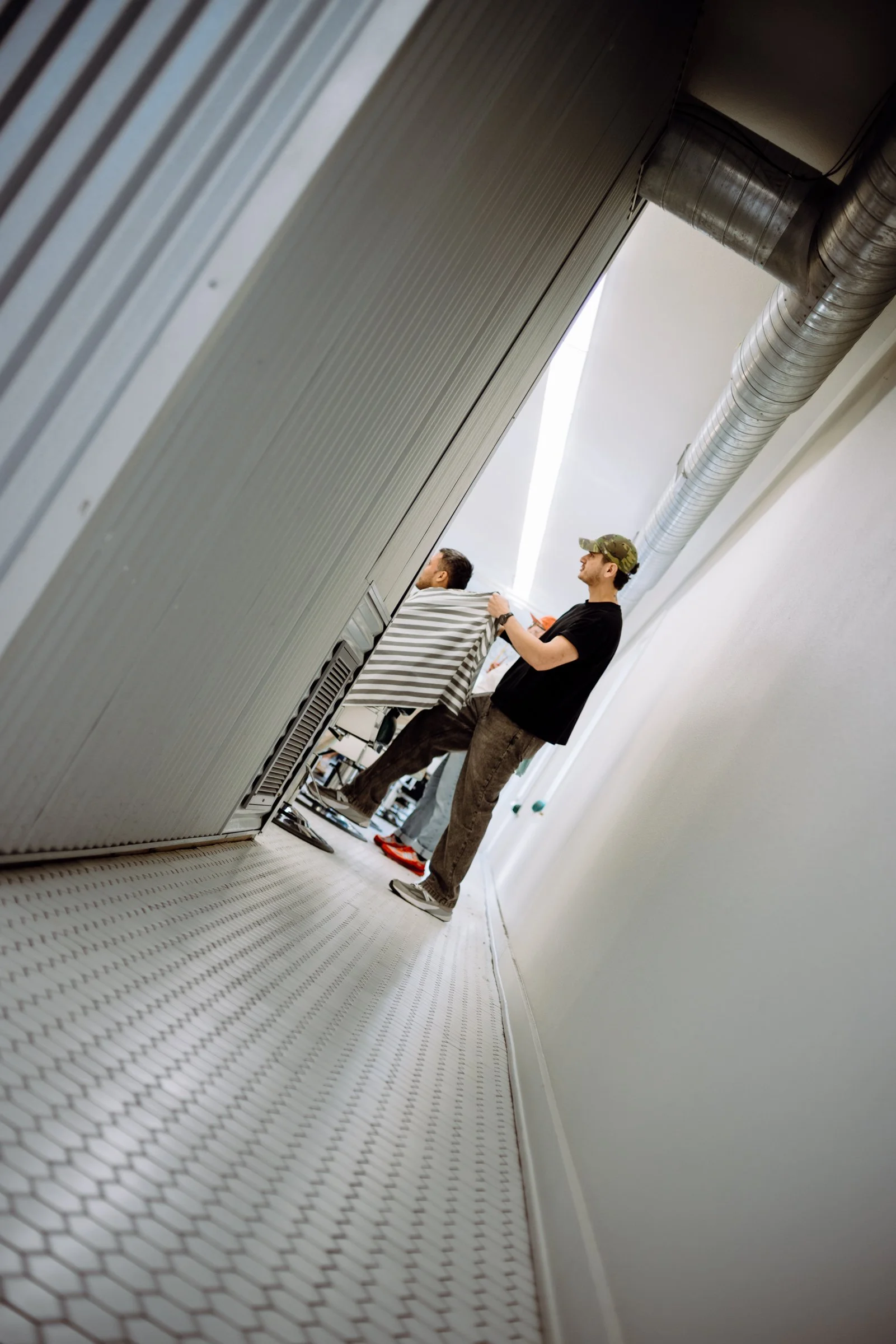 Creative angle of a barber cutting hair inside Honest Barber, a modern men’s barbershop in Austin TX.