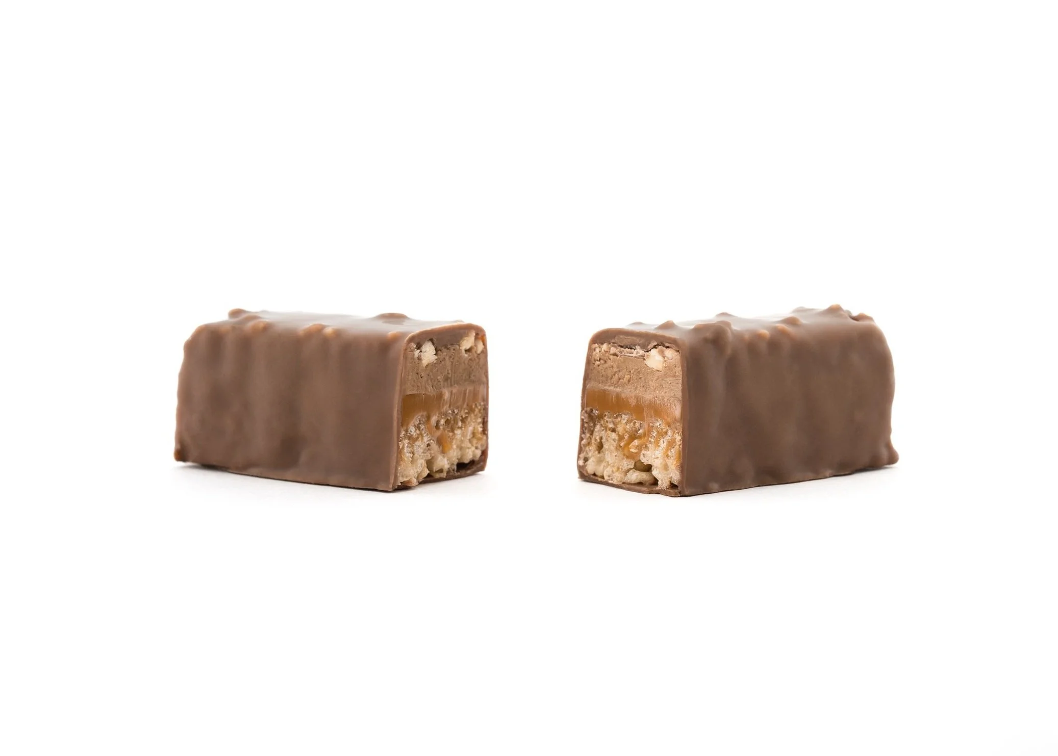 Cross-section of Jean-Marie Auboine Chocolatier's Lion Bar showing layers of crispy rice, sea salt caramel, homemade hazelnut praline, chopped almonds, and Felchlin milk chocolate.