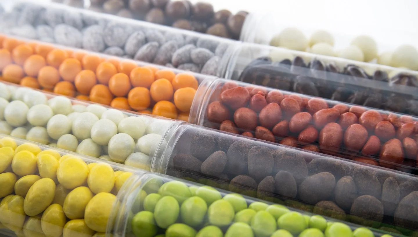 Chocolate, nuts &amp; fruit - the perfect trio. Our panning tubes (available in 4oz &amp; 8oz) are filled with caramelized nuts and dried fruits coated either in dark, milk, or white chocolate. Customizable labels make them ideal for personalized gif