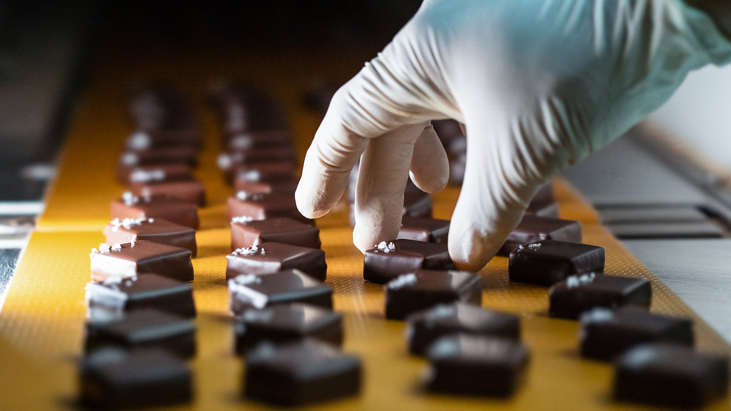 Finished handcrafted chocolate bonbons coming out of the enrobing machine