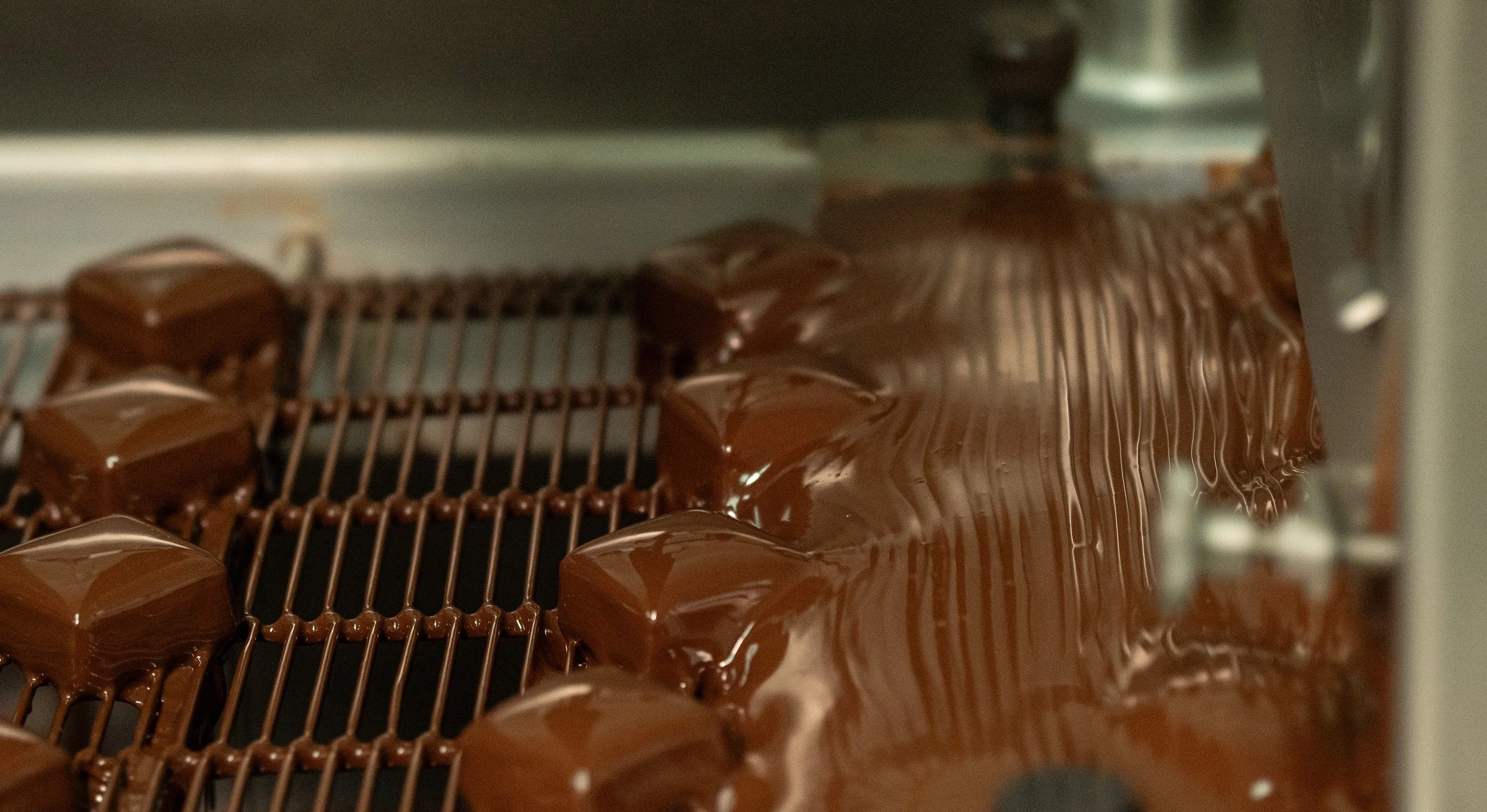 Chocolate bonbons getting enrobed in chocolate in the Jean-Marie Auboine Chocolatier kitchen