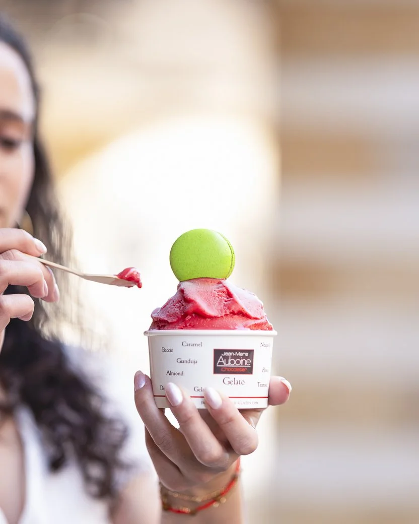 Raspberry gelato with a pistachio macaron being eaten at the jean-marie auboine chocolatier tivoli store