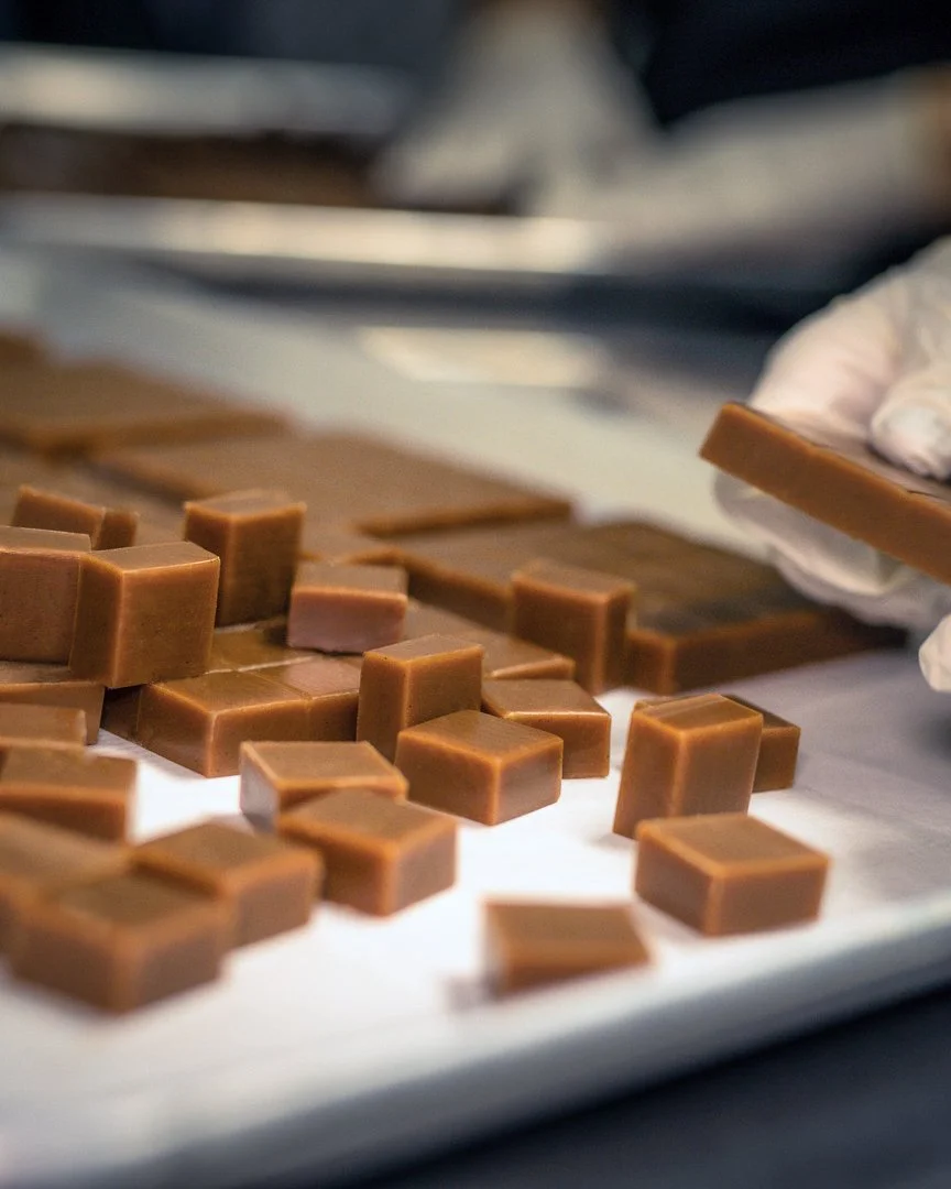 Close-up of premium handcrafted caramels being cut by a chocolatier, showcasing artisanal quality and texture