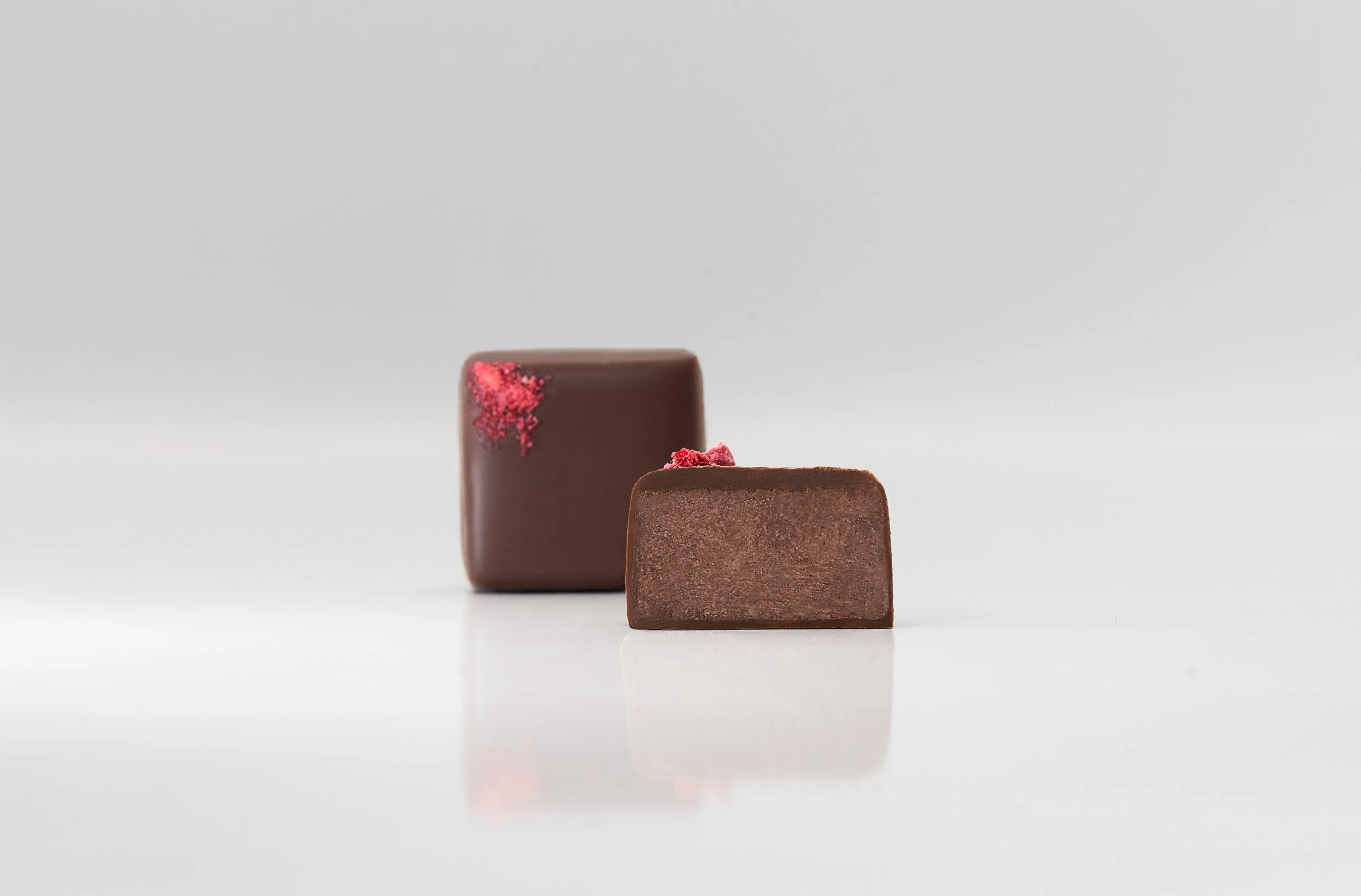 Chocolate bonbon cut open showing smooth ganache filling