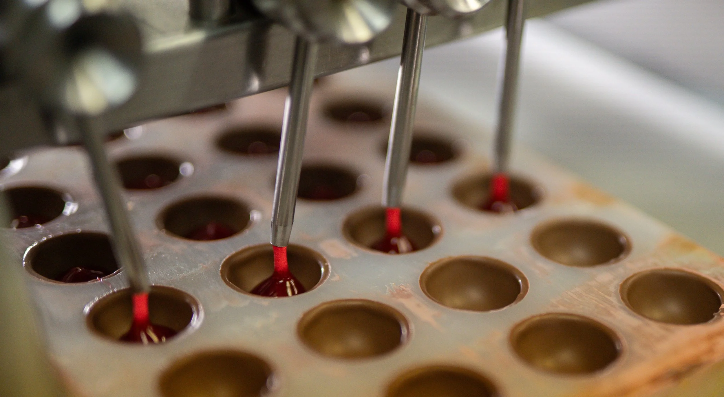 Chocolate shells being filled with ganache at Jean-Marie Auboine Factory