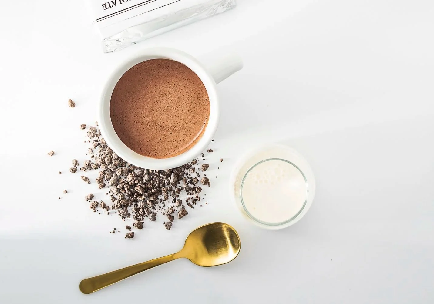 Gourmet drinking chocolate with rich cocoa crumbles, warm milk, and a gold spoon in a luxury presentation