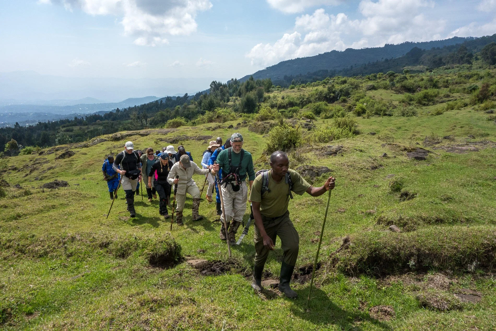 Local guide and porter assisting trekkers through the steep terrain of Volcanoes National Park.