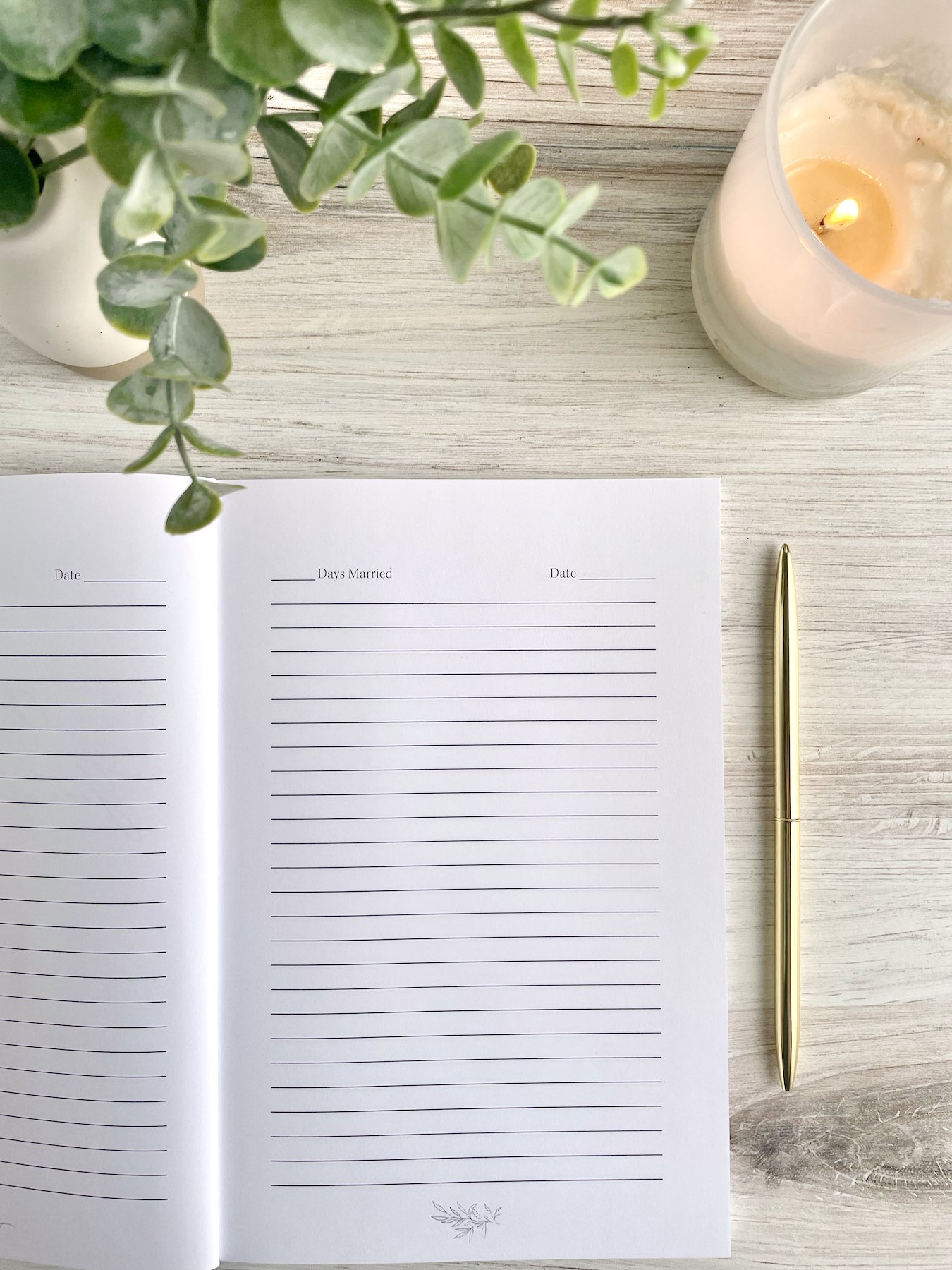 Our First Year of Marriage journal opened to a lined page for journaling. The header provides a small space for "Days married" and "Date." A gold pen and white candle are visible.