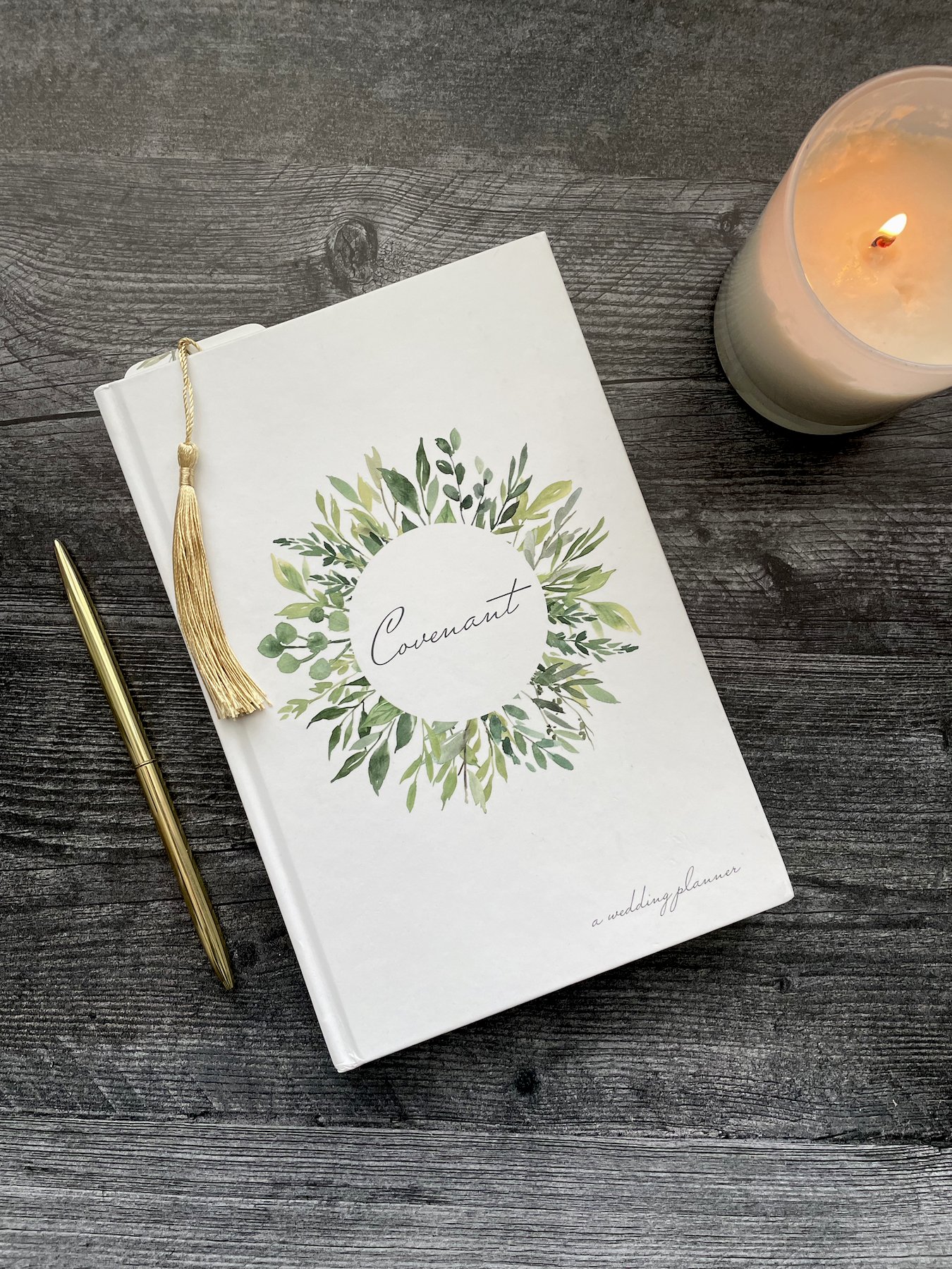 White Covenant Wedding Planner resting on a table with gold tassel from bookmark poking out.