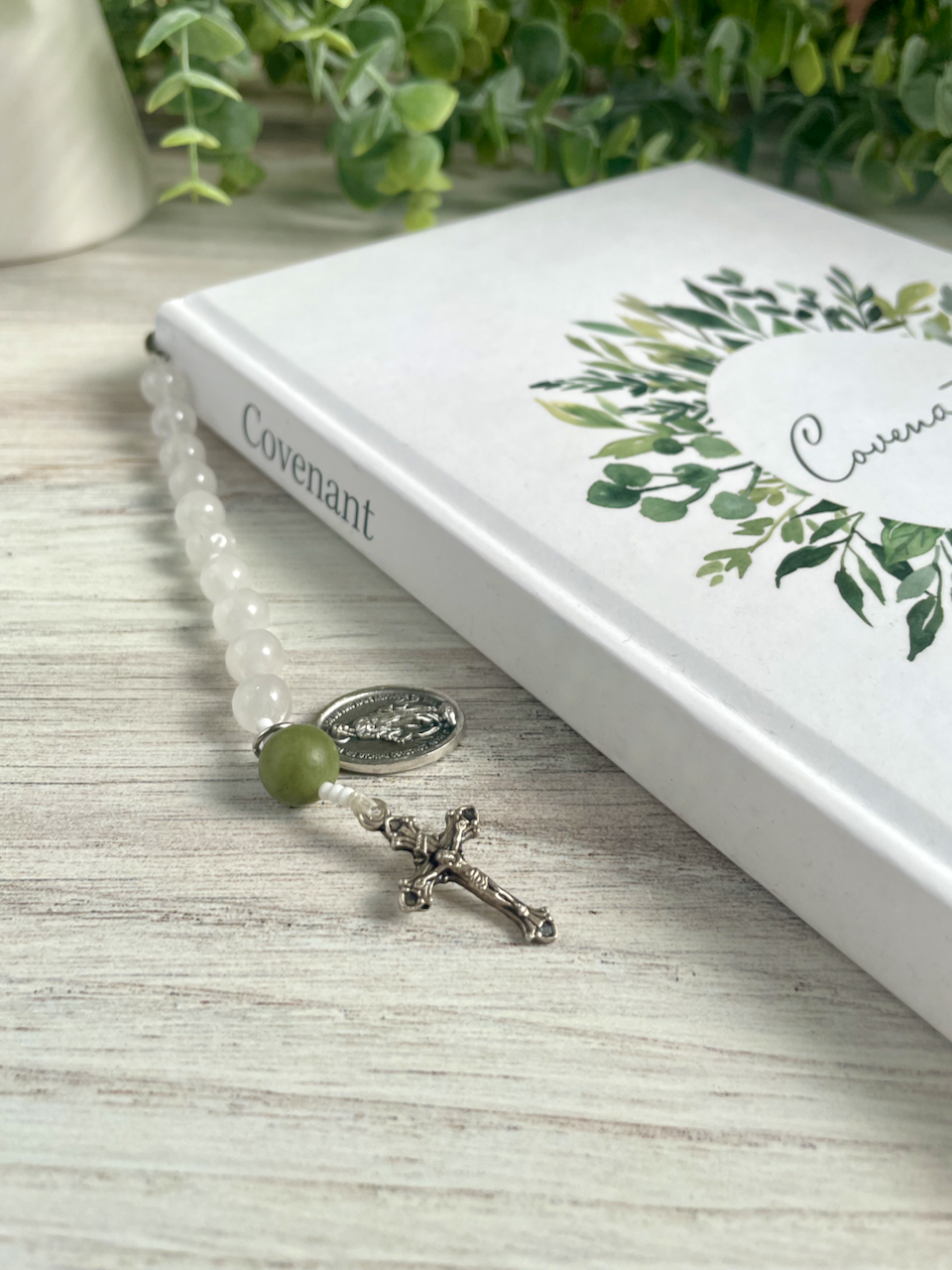 Gemstone bookmark with a decade's worth of rosary beads, miraculous medal, and small crucifix, hanging out of the Covenant Wedding Planner.
