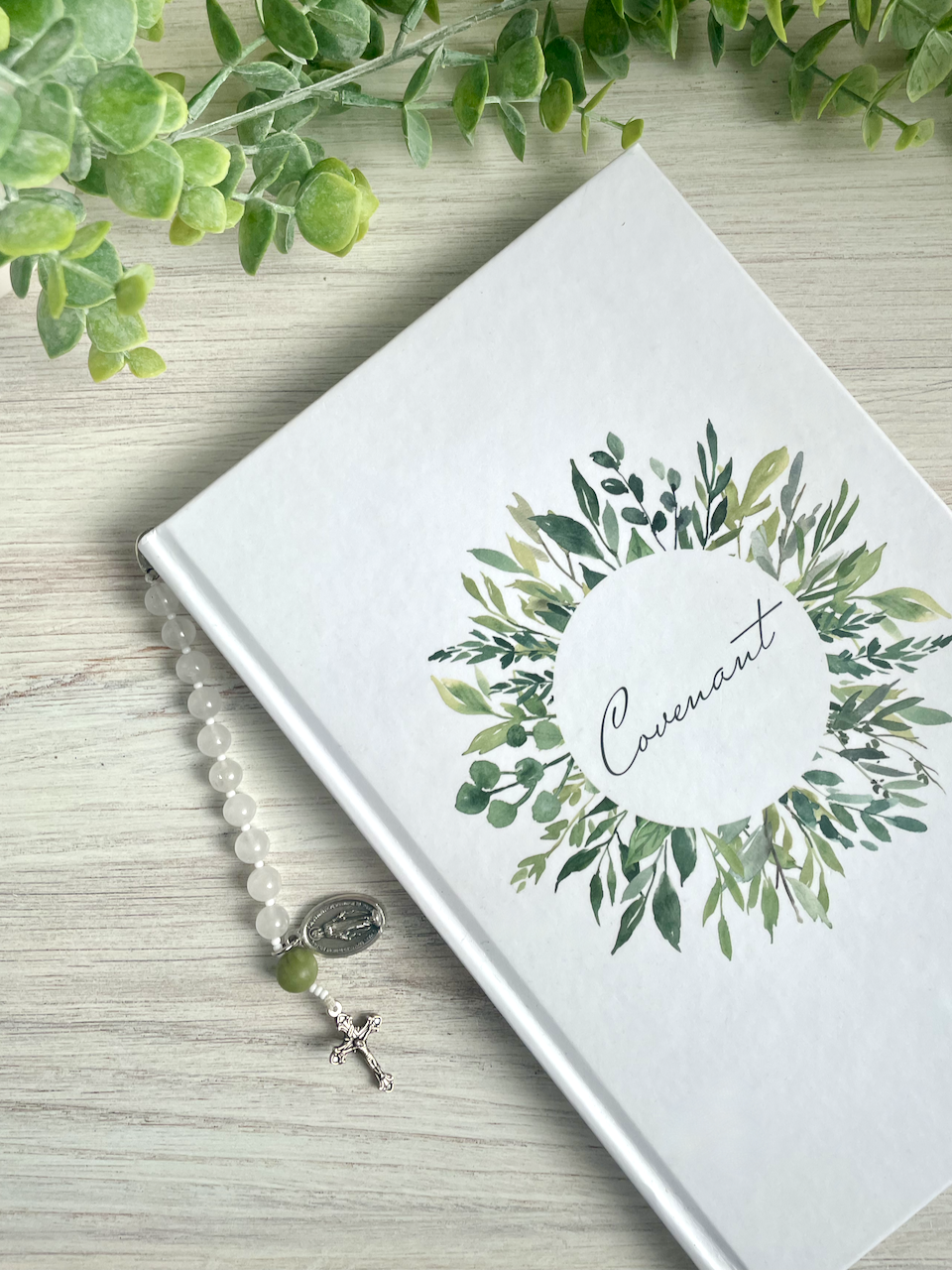 Gemstone bookmark with a decade's worth of rosary beads, miraculous medal, and small crucifix, hanging out of the Covenant Wedding Planner.