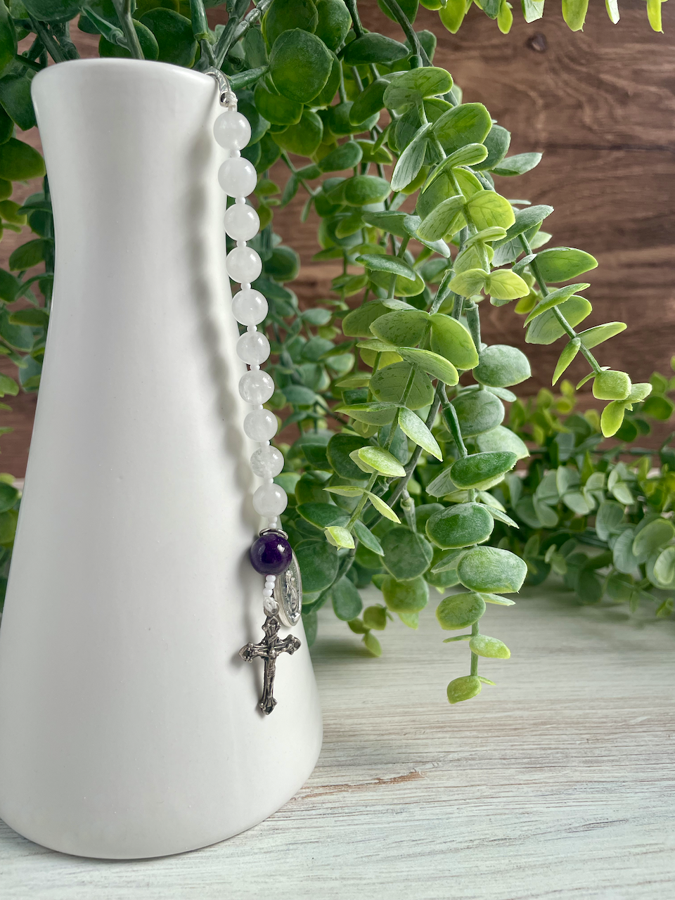 Gemstone bookmark with a decade's worth of rosary beads, miraculous medal, and small crucifix, hanging from a vase. Purple Our Father bead.