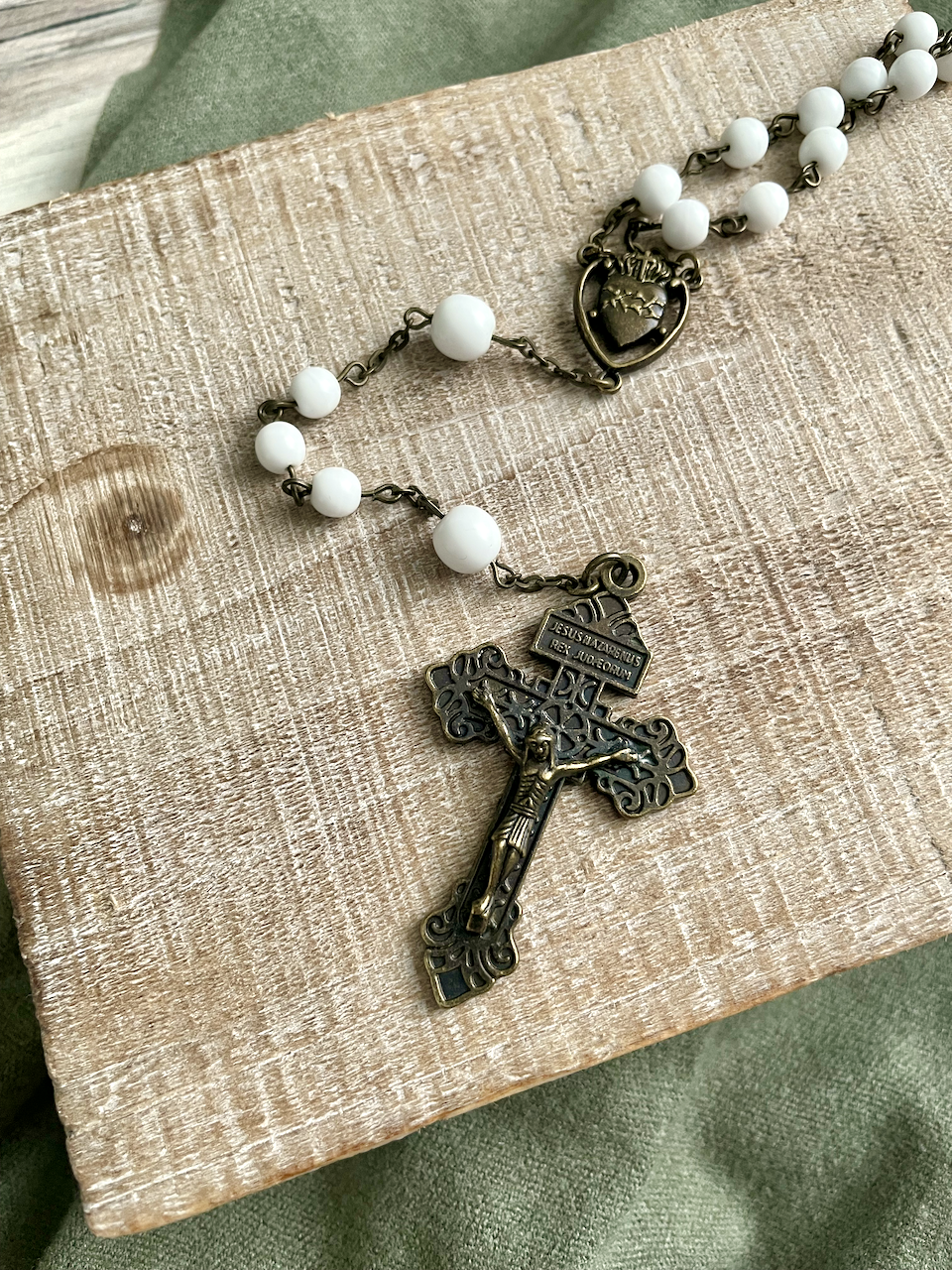 Smooth white beaded rosary with bronze chain links. Bronze pardon crucifix and bronze Sacred Heart centerpiece.