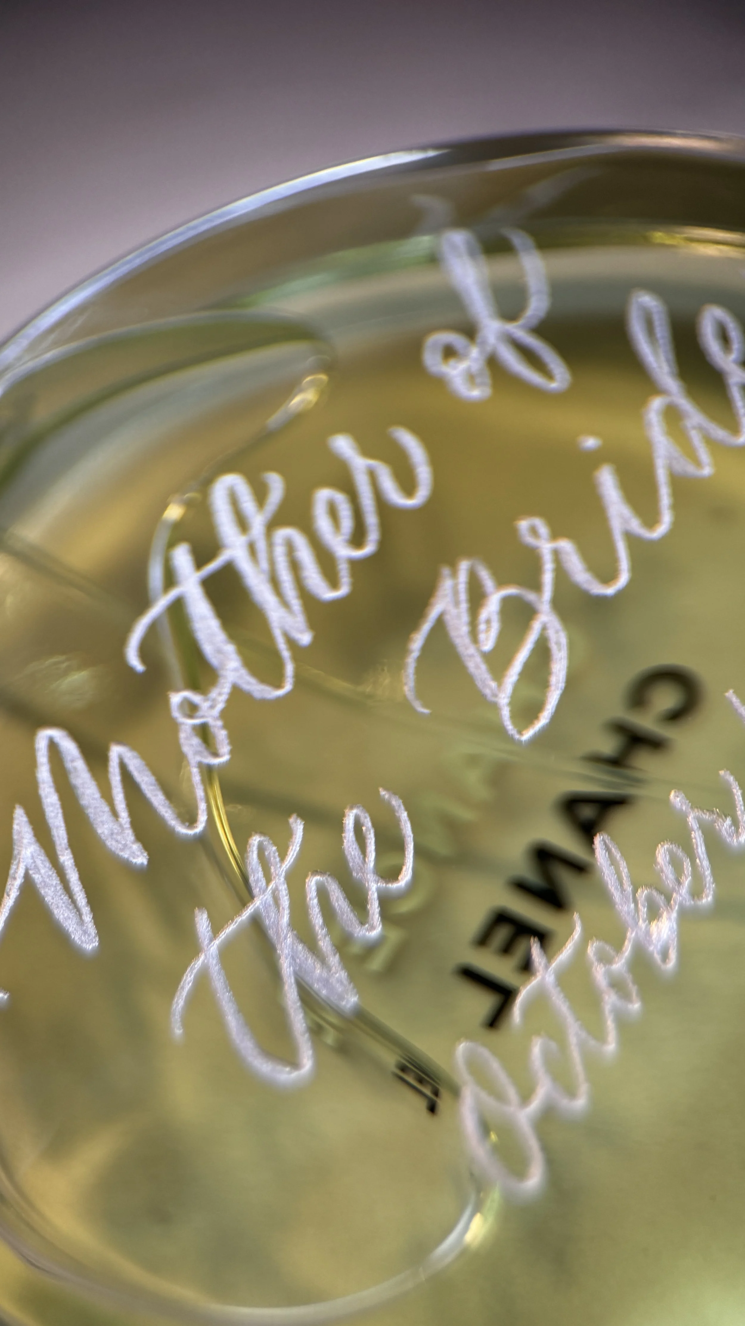 Close-up of a glass with handwritten white text and a black word 'THANK' visible inside the glass, with a blurred background.