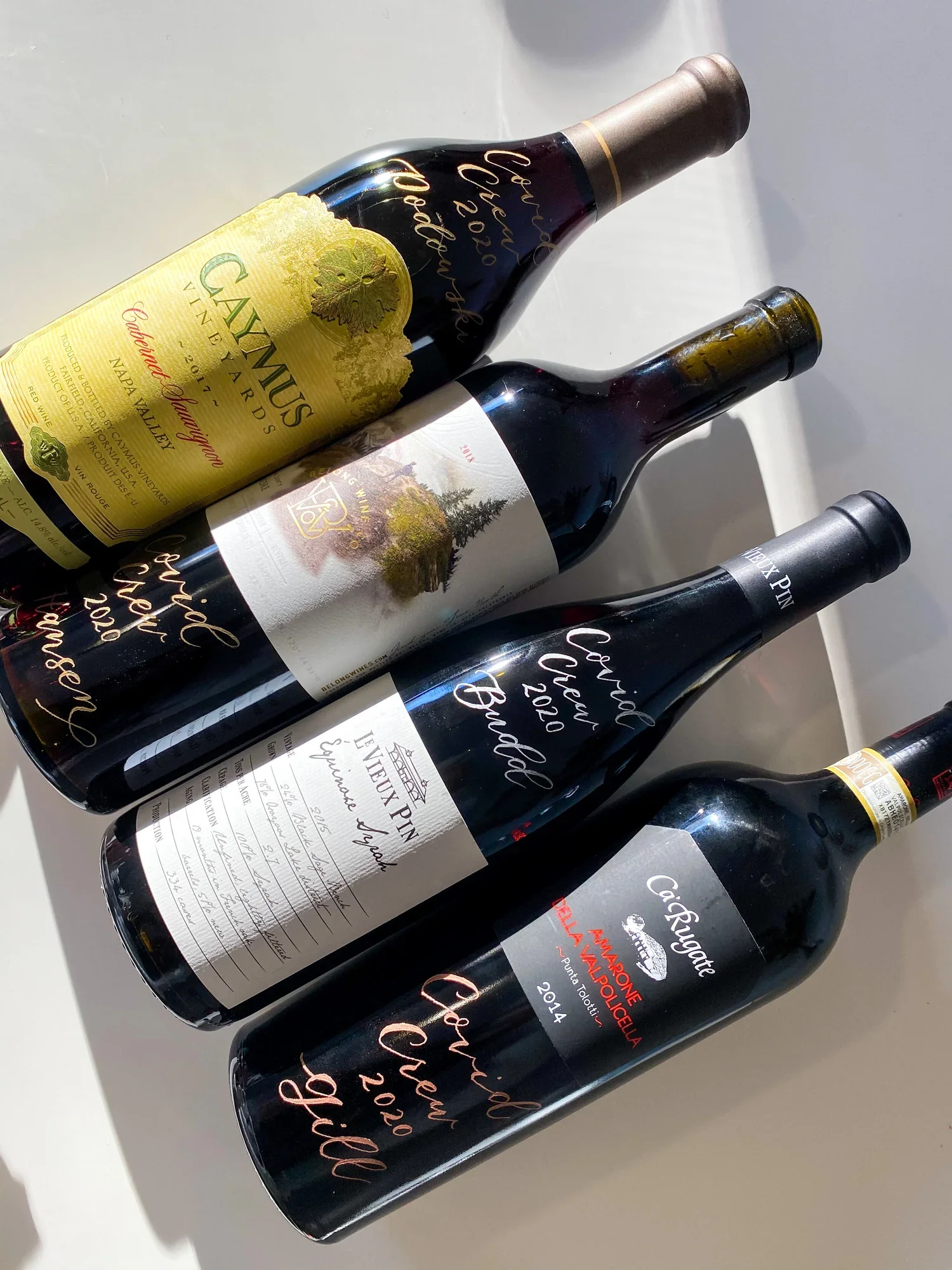 Four bottles of wine, each with unique labels, arranged on a white surface.