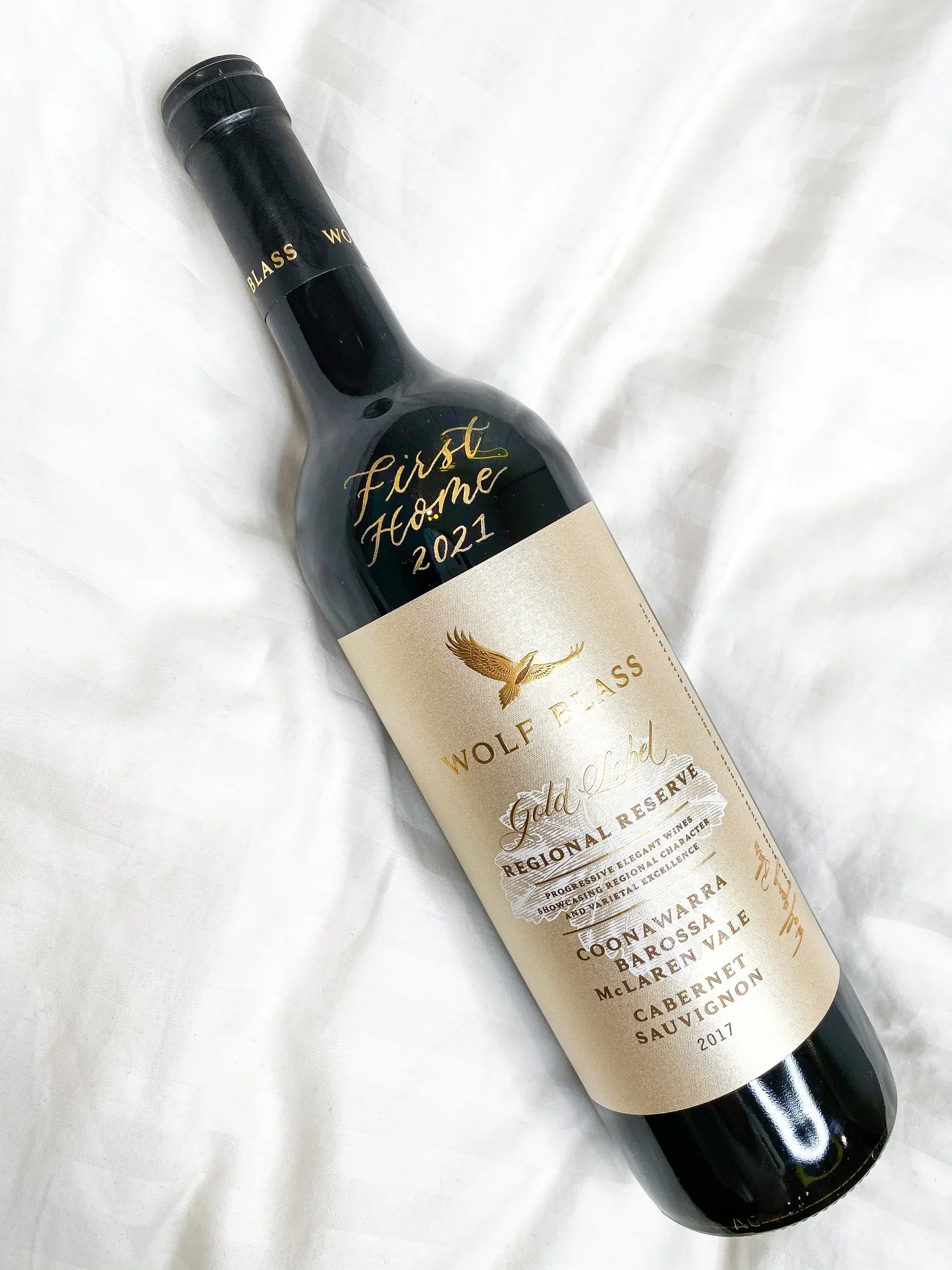 A bottle of Wolf Blass Gold Label regional reserve Cabernet Sauvignon wine, vintage 2017, lying on white fabric.