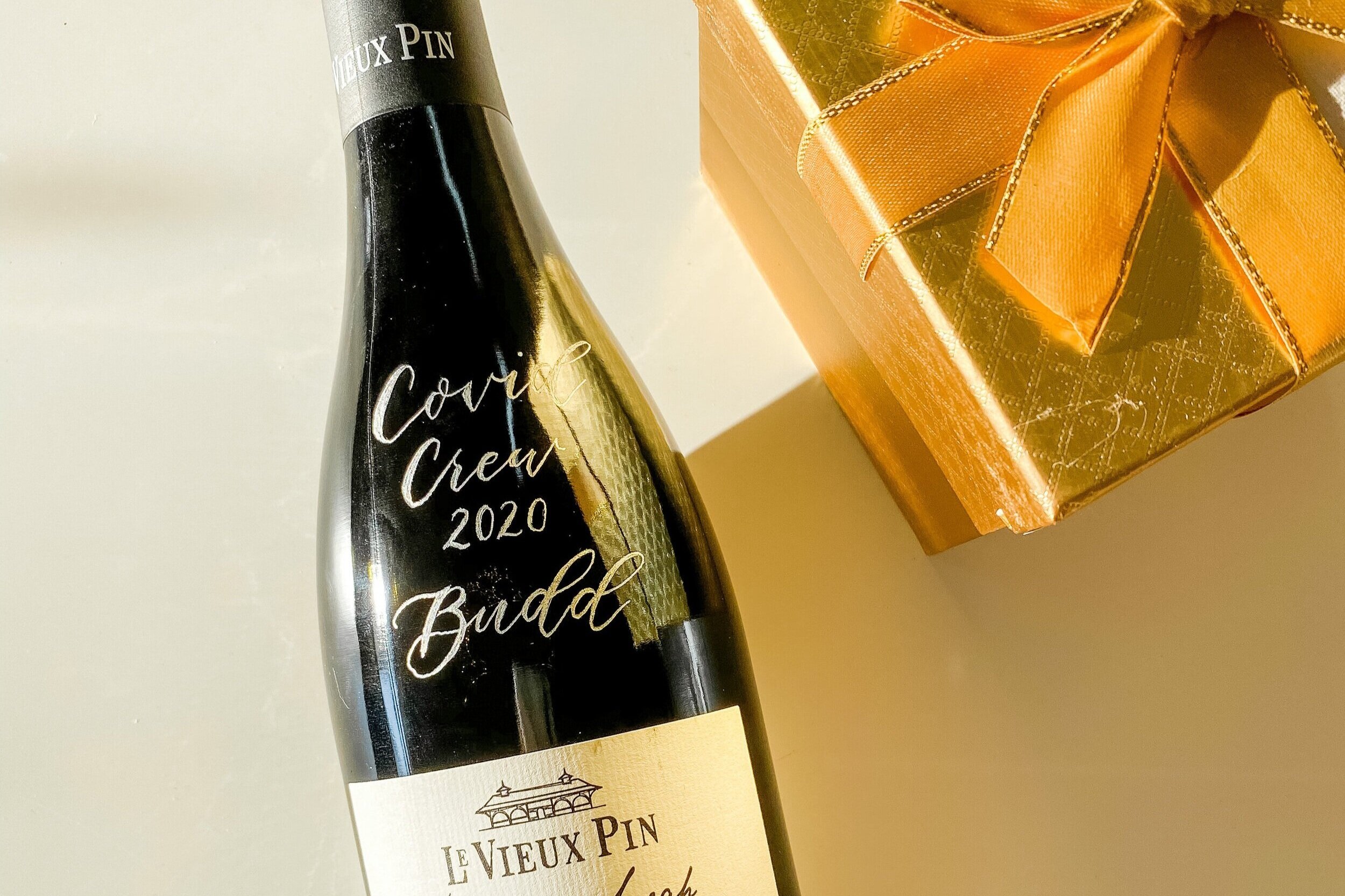engraved wine bottle beside a golden gift box