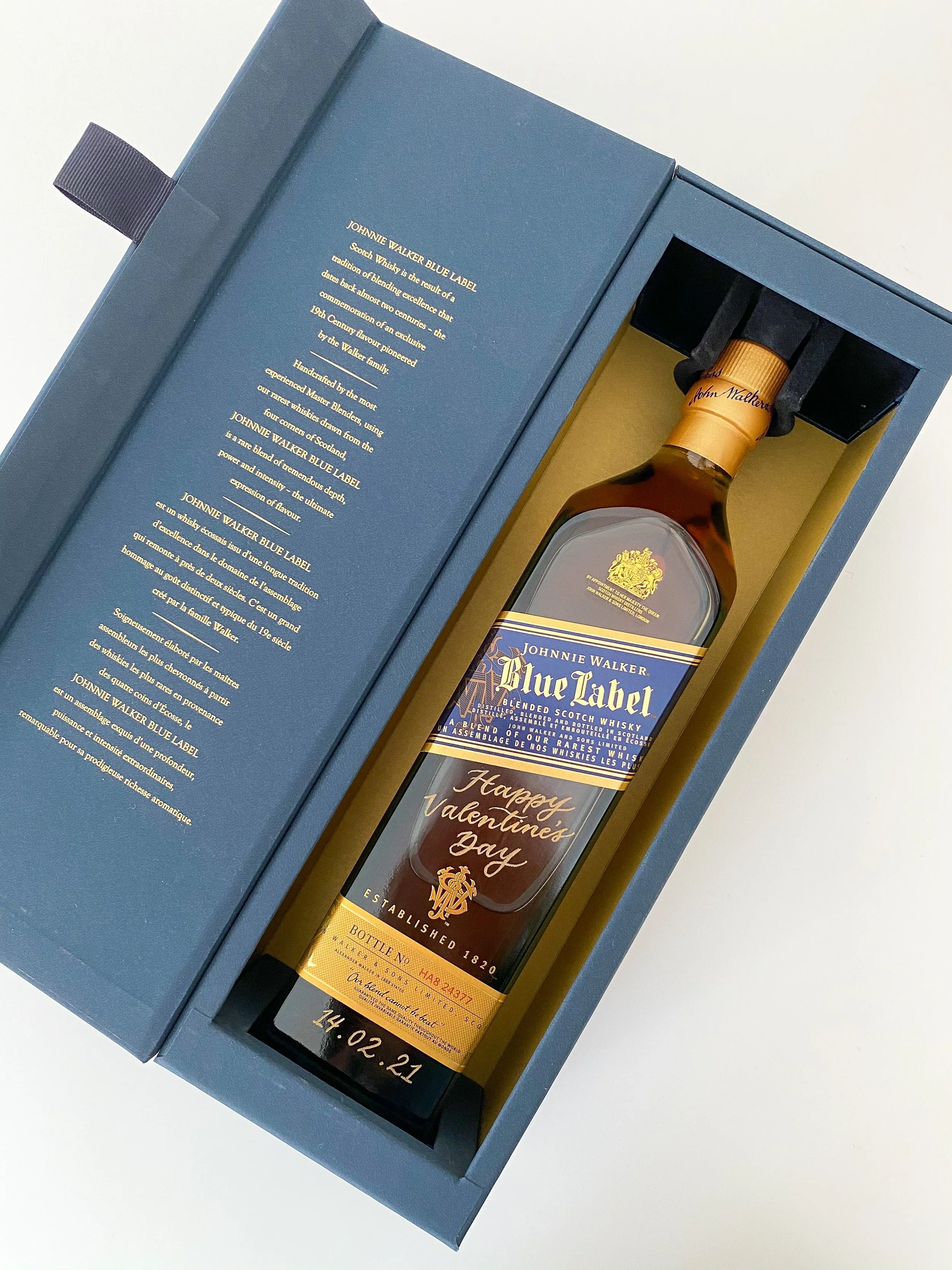 A bottle of Johnnie Walker Blue Label whisky inside a blue box with a gold interior, with a Valentine's Day message on the bottle.