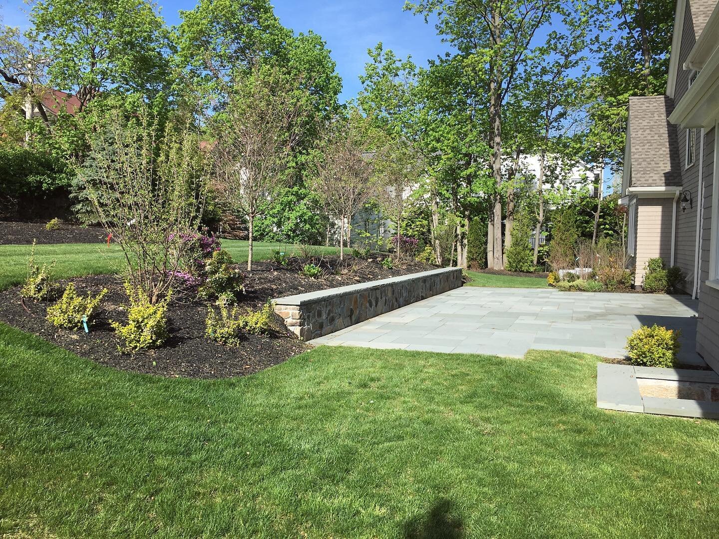 A functional outdoor space complete with hardscape designed around bluestone patio with retaining wall and landscape beds