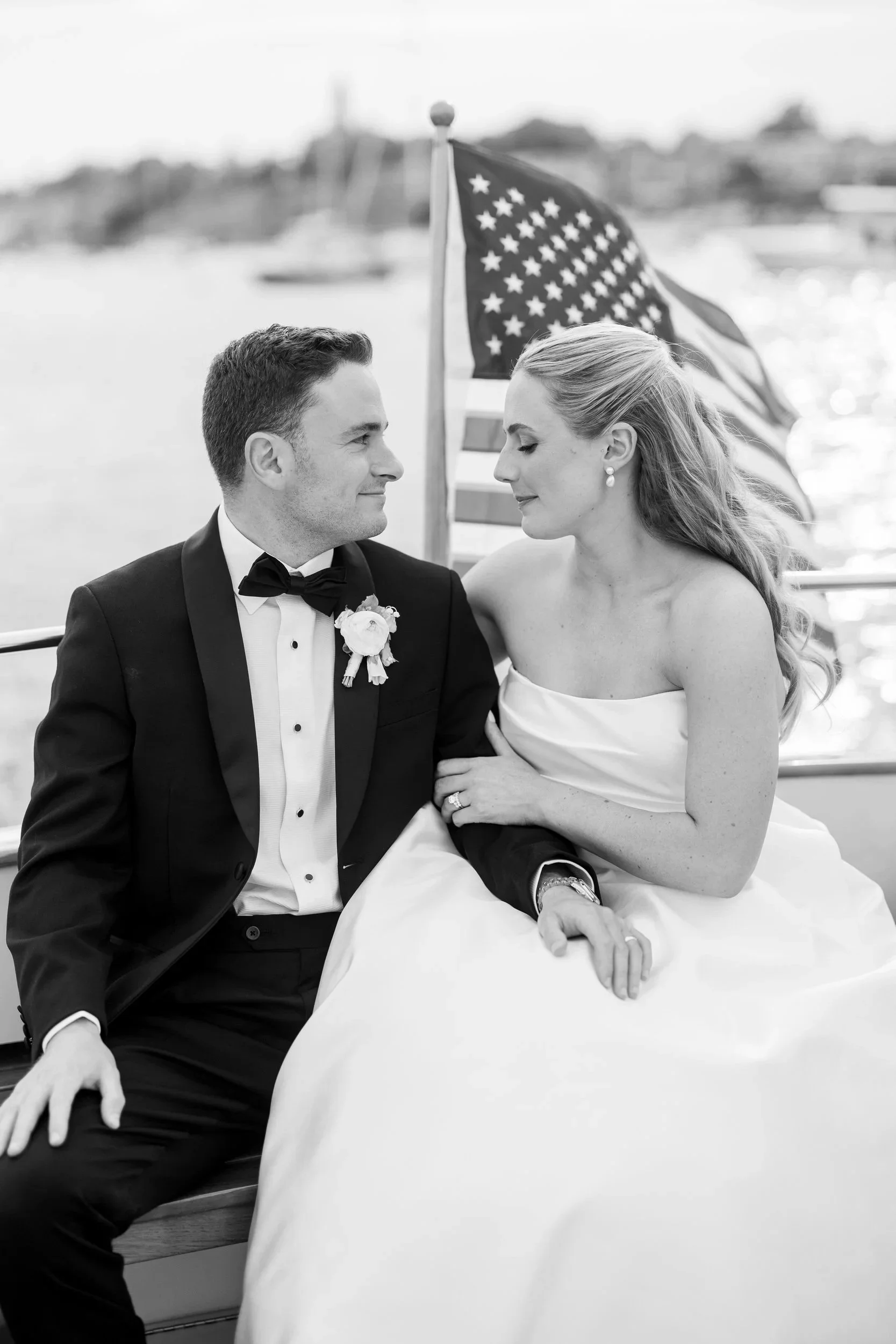 Sunset boat portraits of bride and groom in Marblehead Harbor surrounded by sailboats during their wedding celebration.