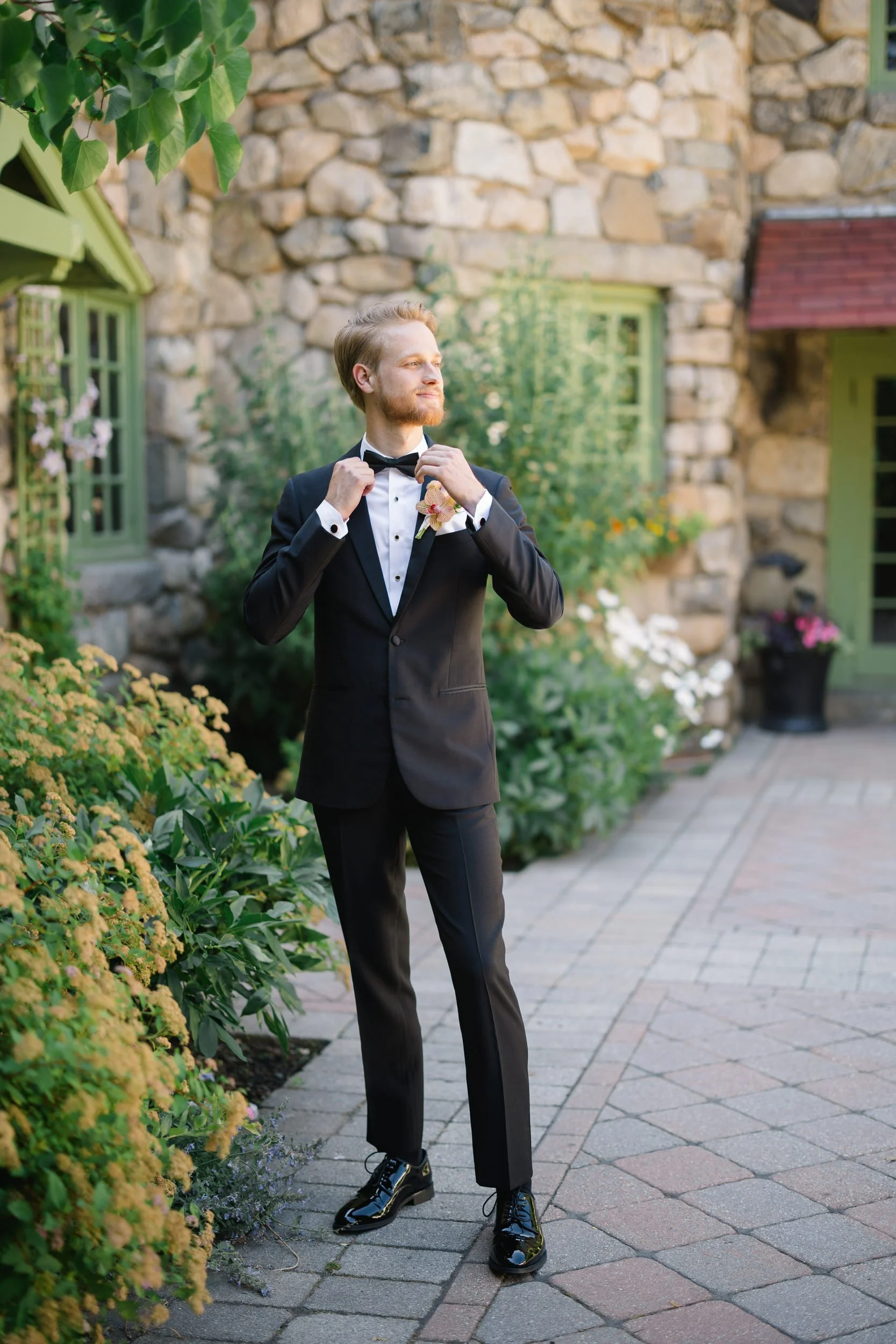 Groom portrait at Willowdale Estate wearing black suit and bow tie in Topsfield Massachusetts garden setting