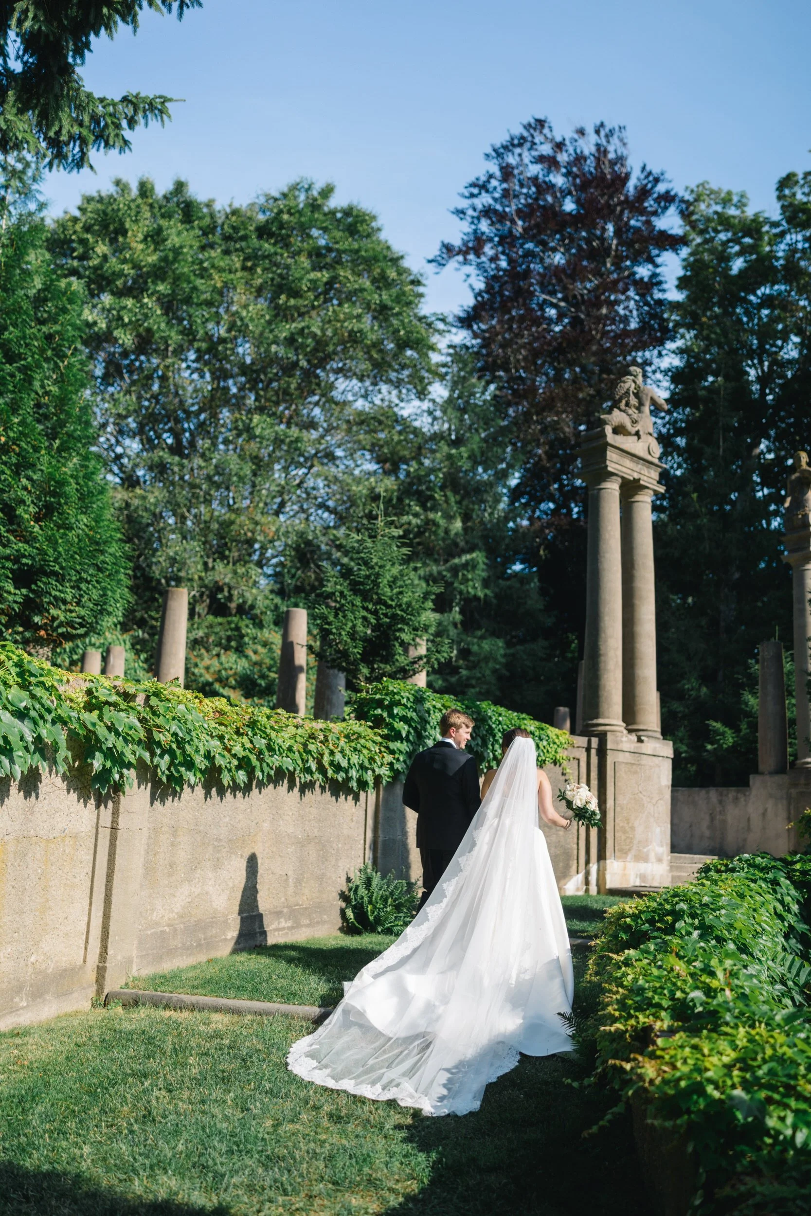 Bride and groom walking hand in hand through the gardens at Crane Estate.