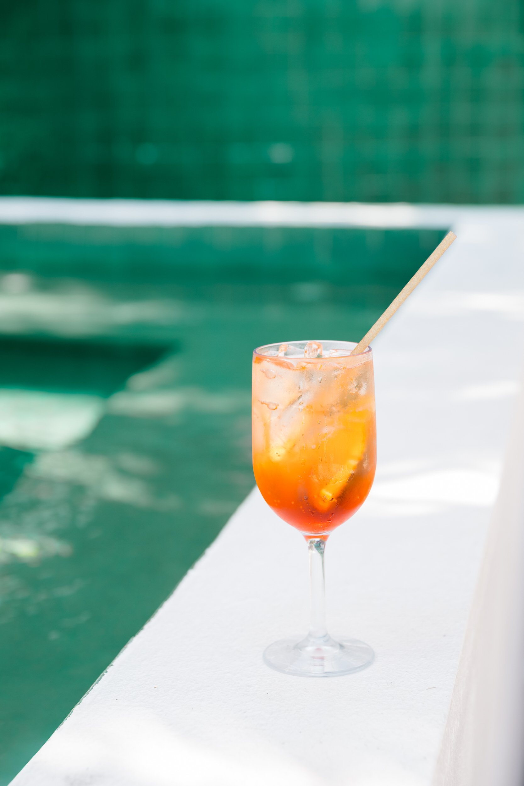 Pink cocktail served against colorful blue tile at The Pink Palm Hotel