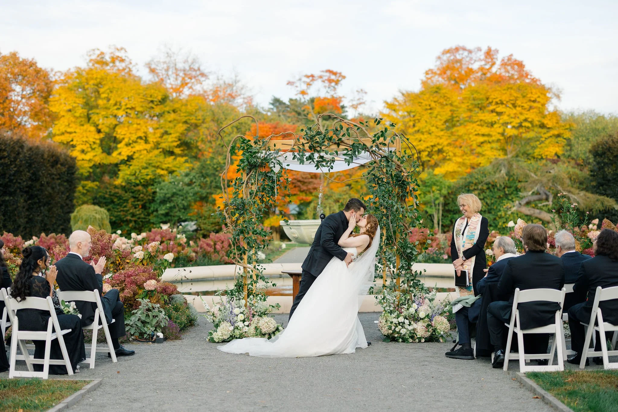Garden wedding ceremony at Elm Bank framed by autumn foliage.