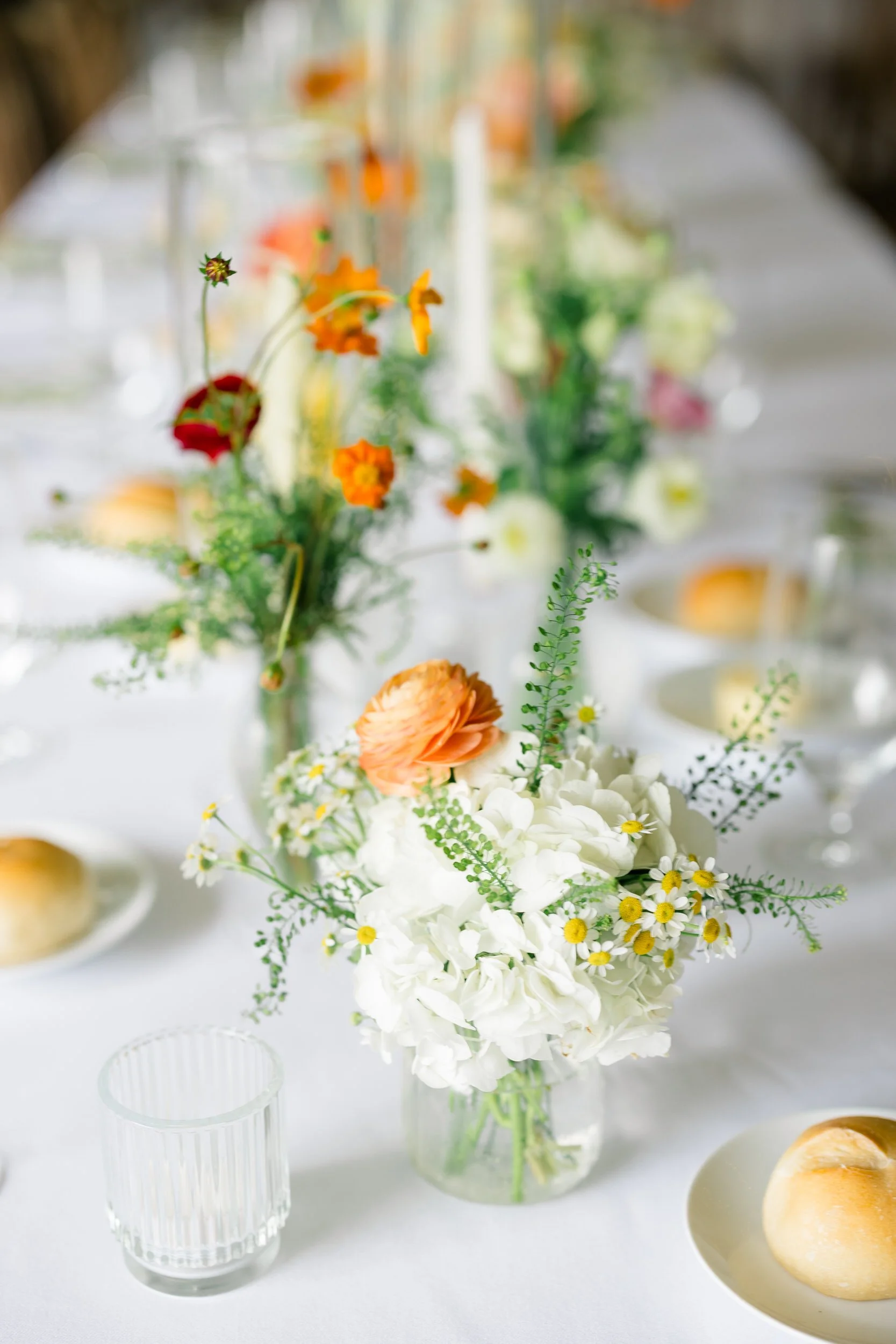 Reception table featuring orange, yellow, pink, and green floral arrangements.