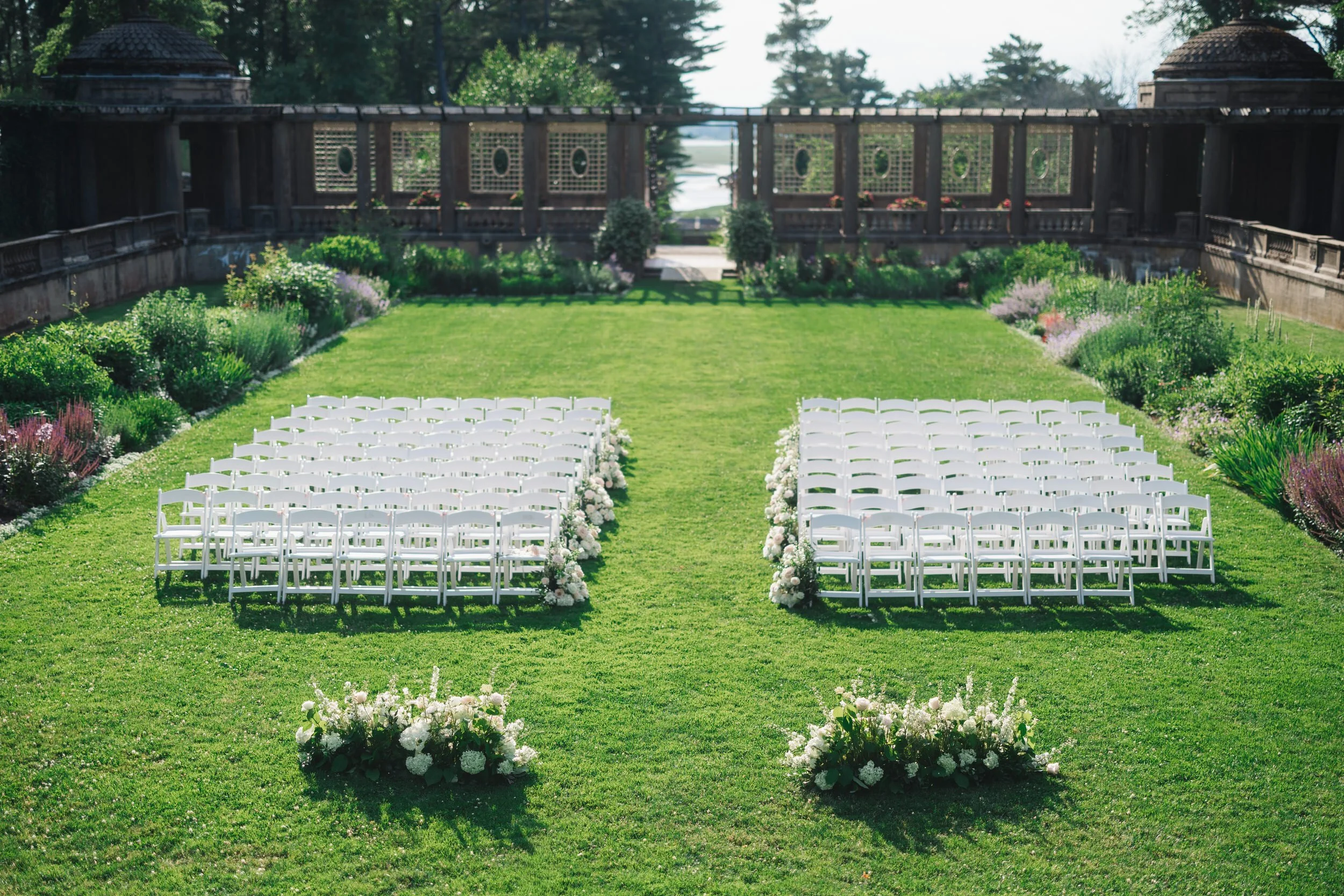 Romantic garden ceremony setup in the Italian Garden at Crane Estate surrounded by lush summer landscaping.