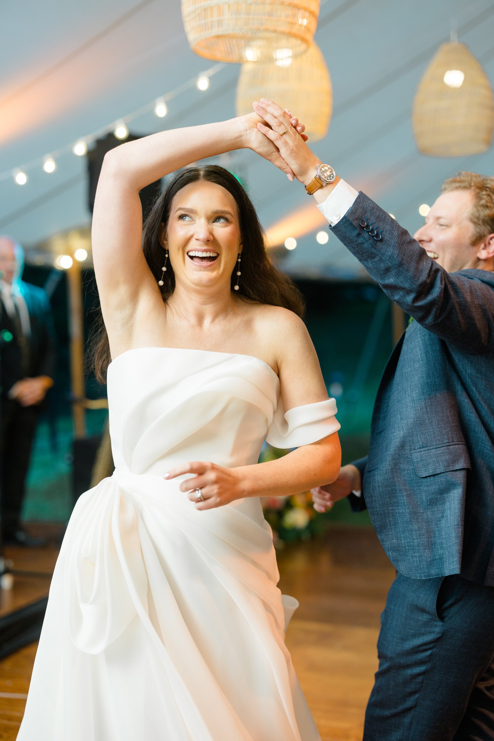 Newlyweds sharing their first dance beneath colorful floral installations at the Connors Center.