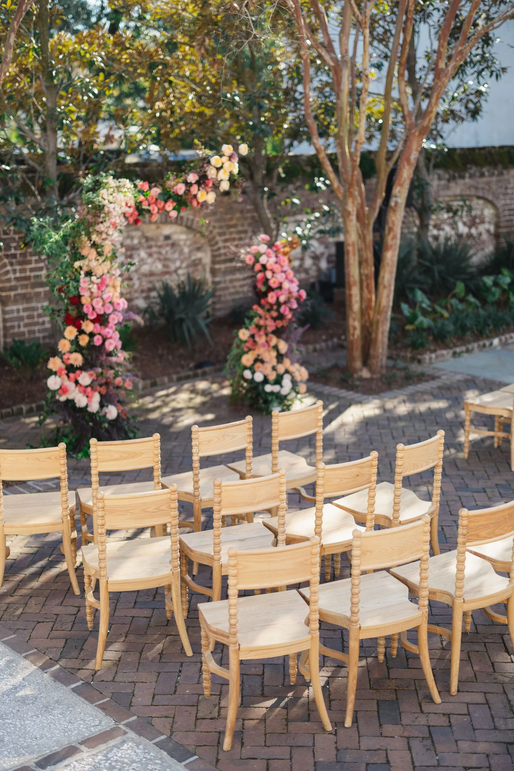 Bride and groom exchanging vows beneath lush pink florals in Charleston, SC.