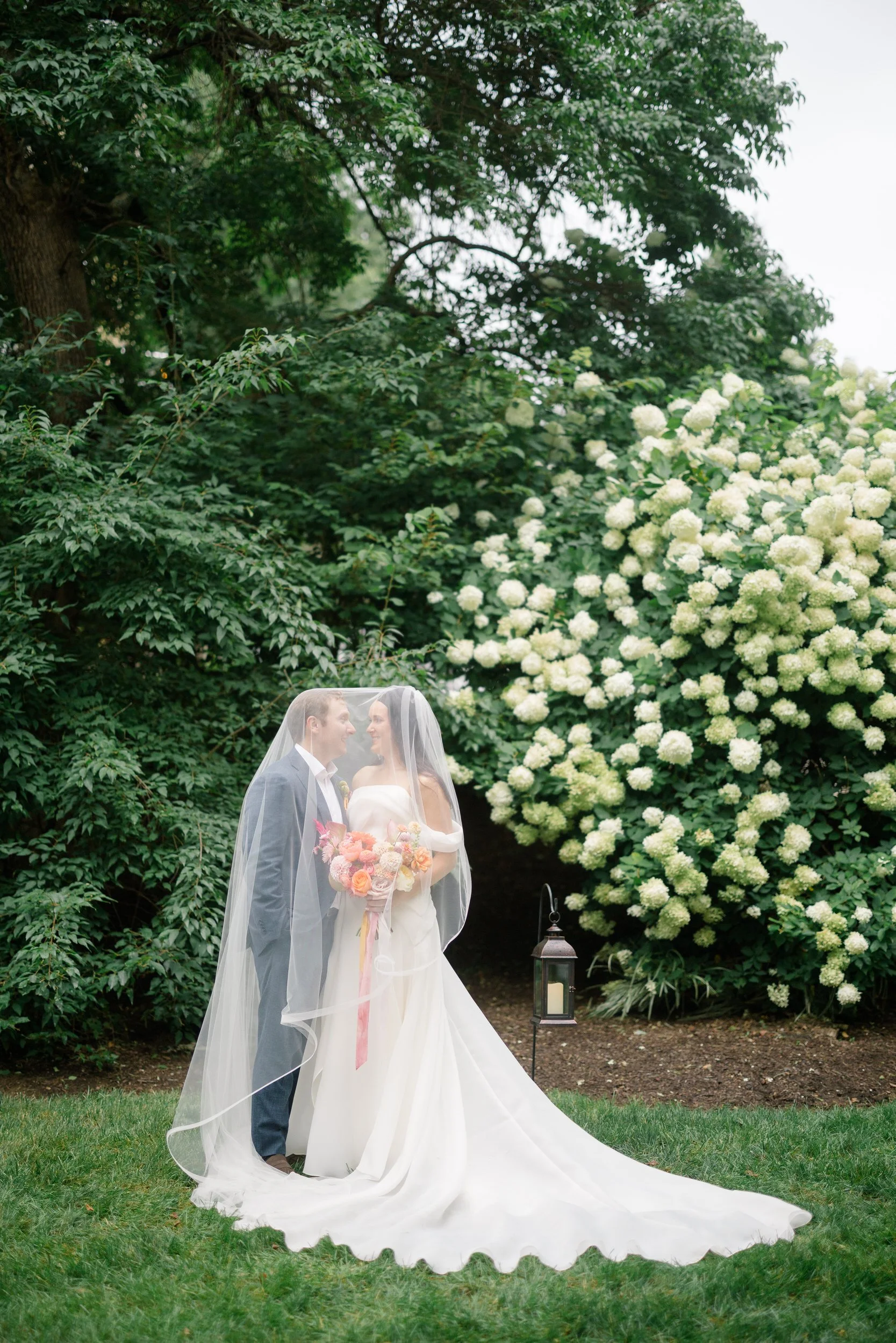 Bride and groom portraits in a vibrant secret garden setting filled with colorful seasonal blooms.