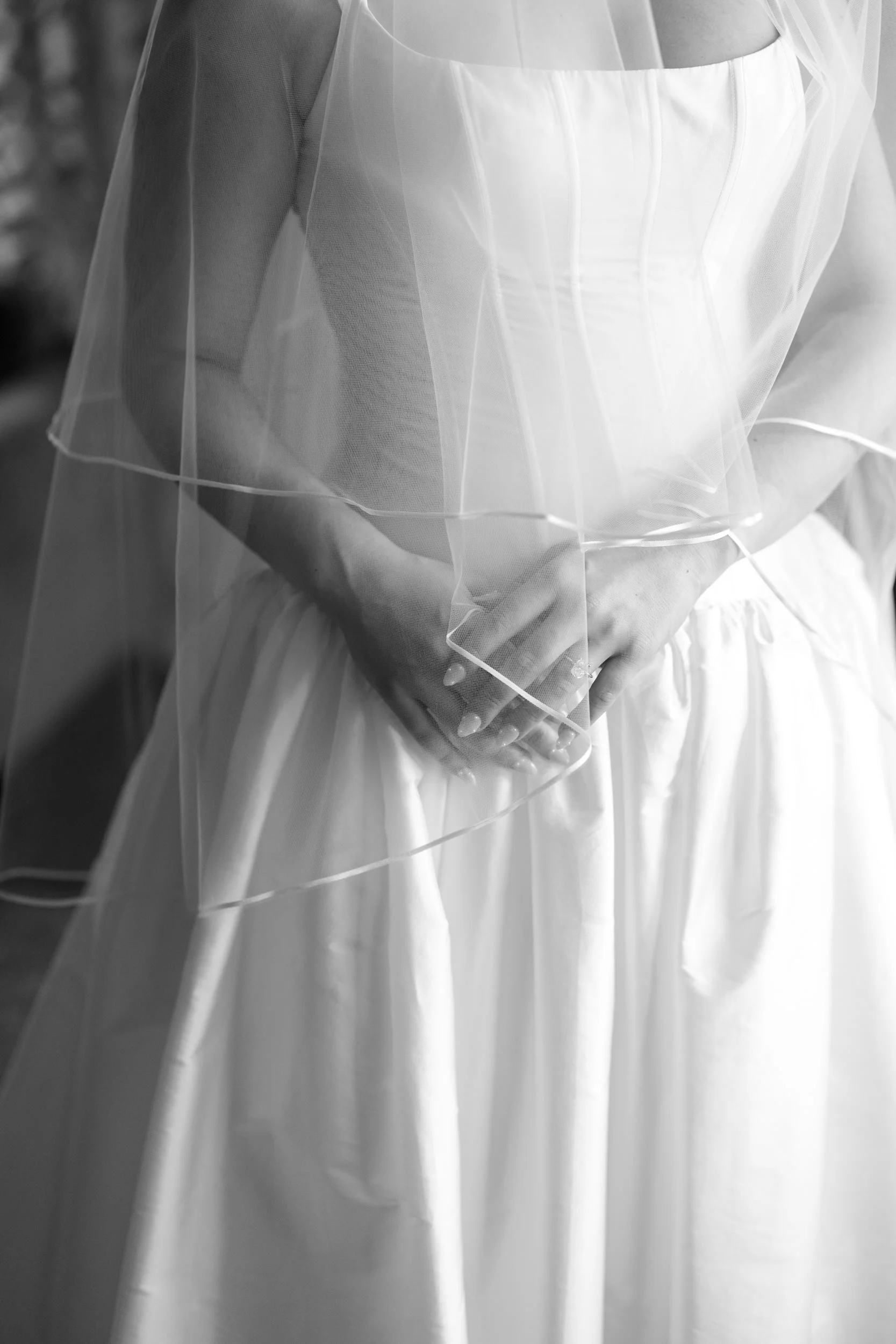 Bridal portrait while getting ready in natural light showcasing basque waist gown and soft veil movement