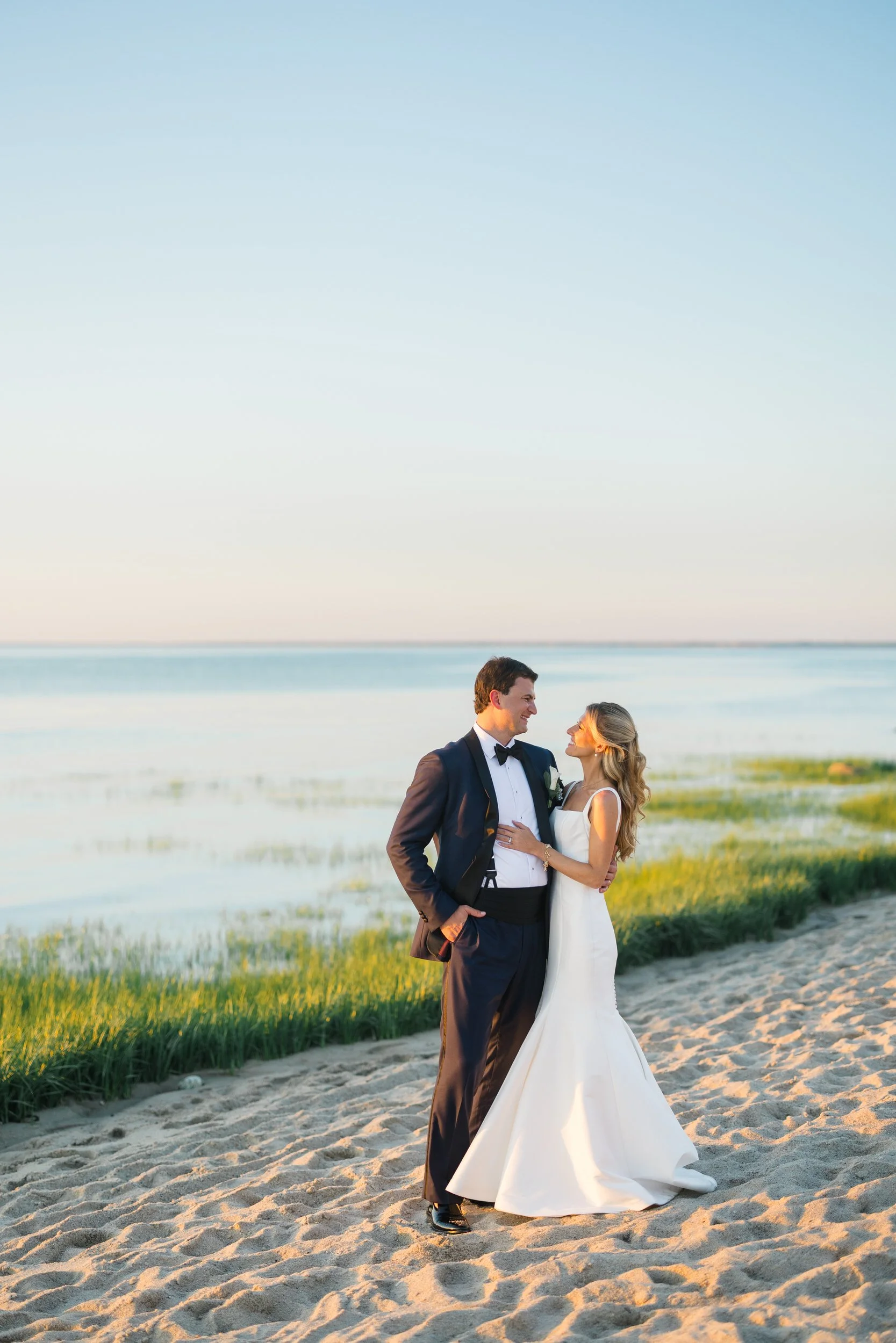 Newlyweds walking along the beach at sunset on Cape Cod