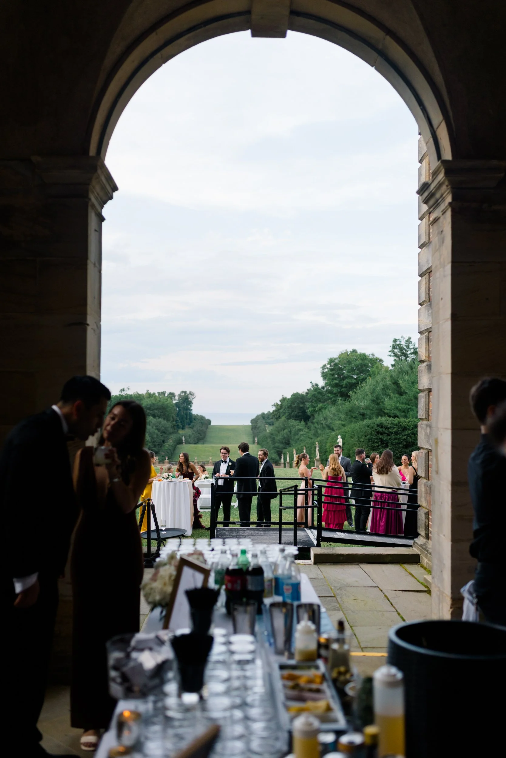 Guests gathered on the lawn at Crane Estate enjoying charcuterie boards and cocktails during golden hour.