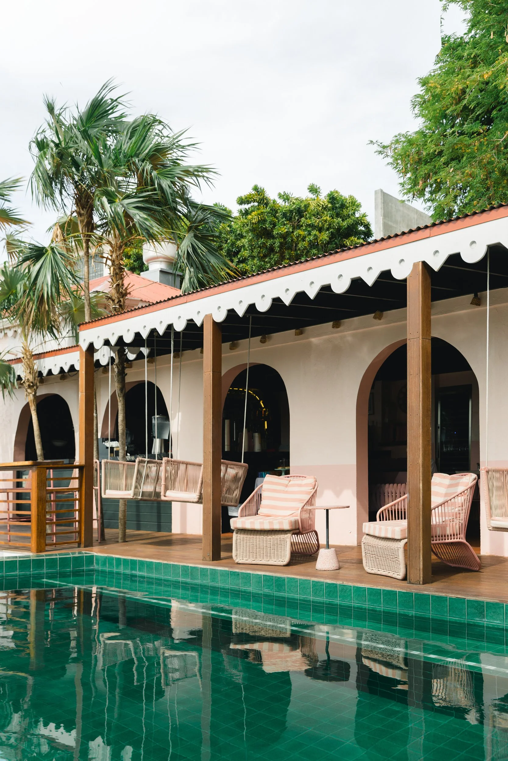 Blue-green tile and tropical landscaping surrounding the pool at The Pink Palm Hotel