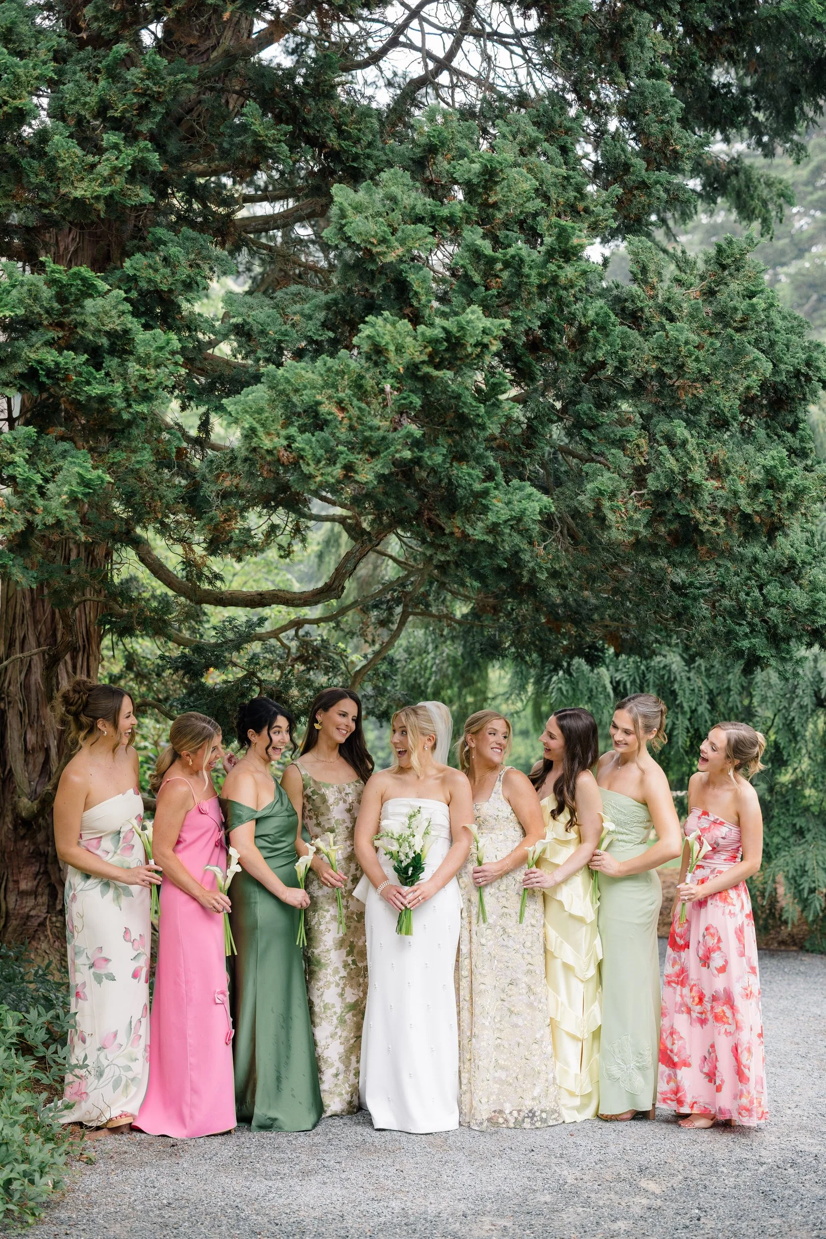 Bridesmaids wearing pink, yellow, and green dresses in the gardens at Blithewold Mansion.